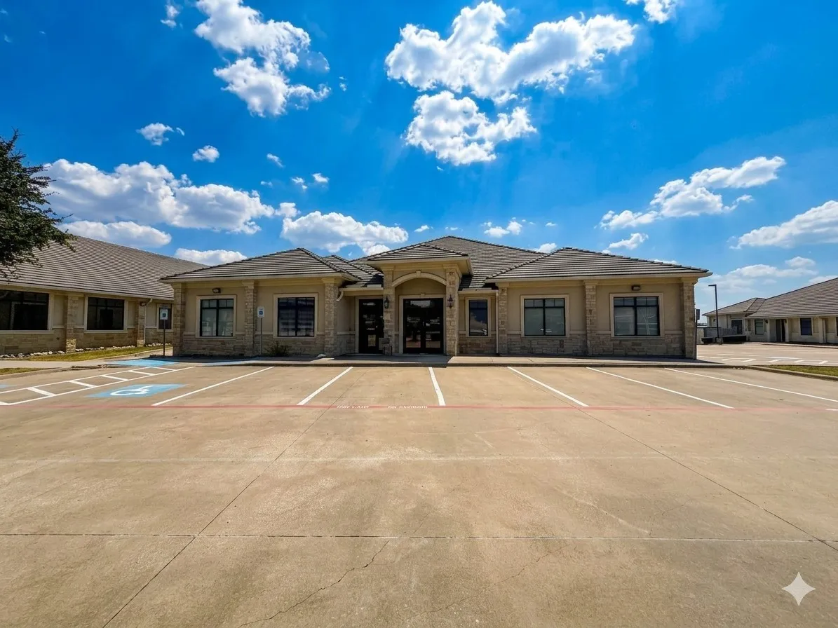 Contemporary commercial building featuring a stone and stucco exterior, dark-framed windows, and a large paved parking area