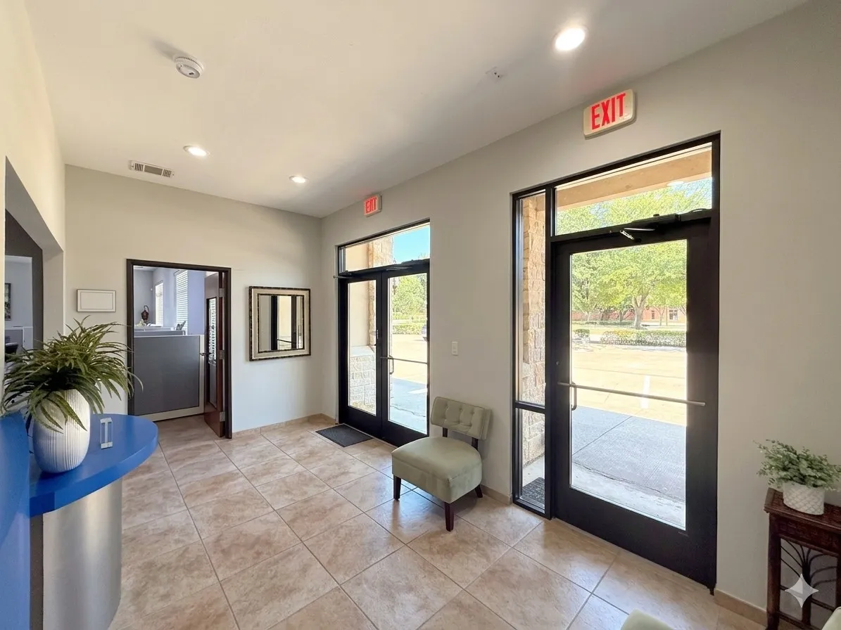 Recessed ceiling lighting illuminates the tiled flooring and glass entry doors