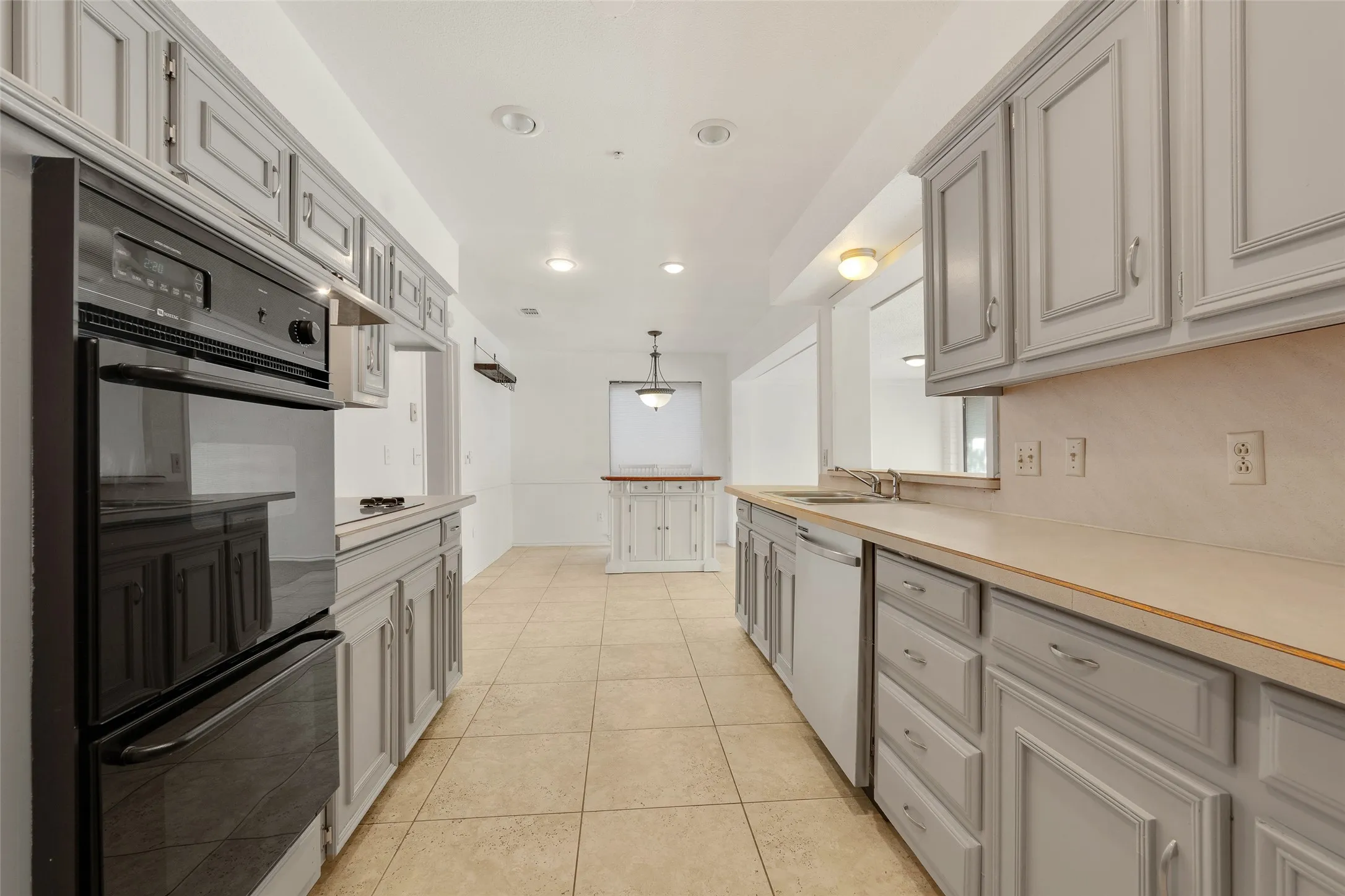 Kitchen featuring extensive cabinetry, integrated wall oven, countertop workspace, tile flooring, and recessed lighting