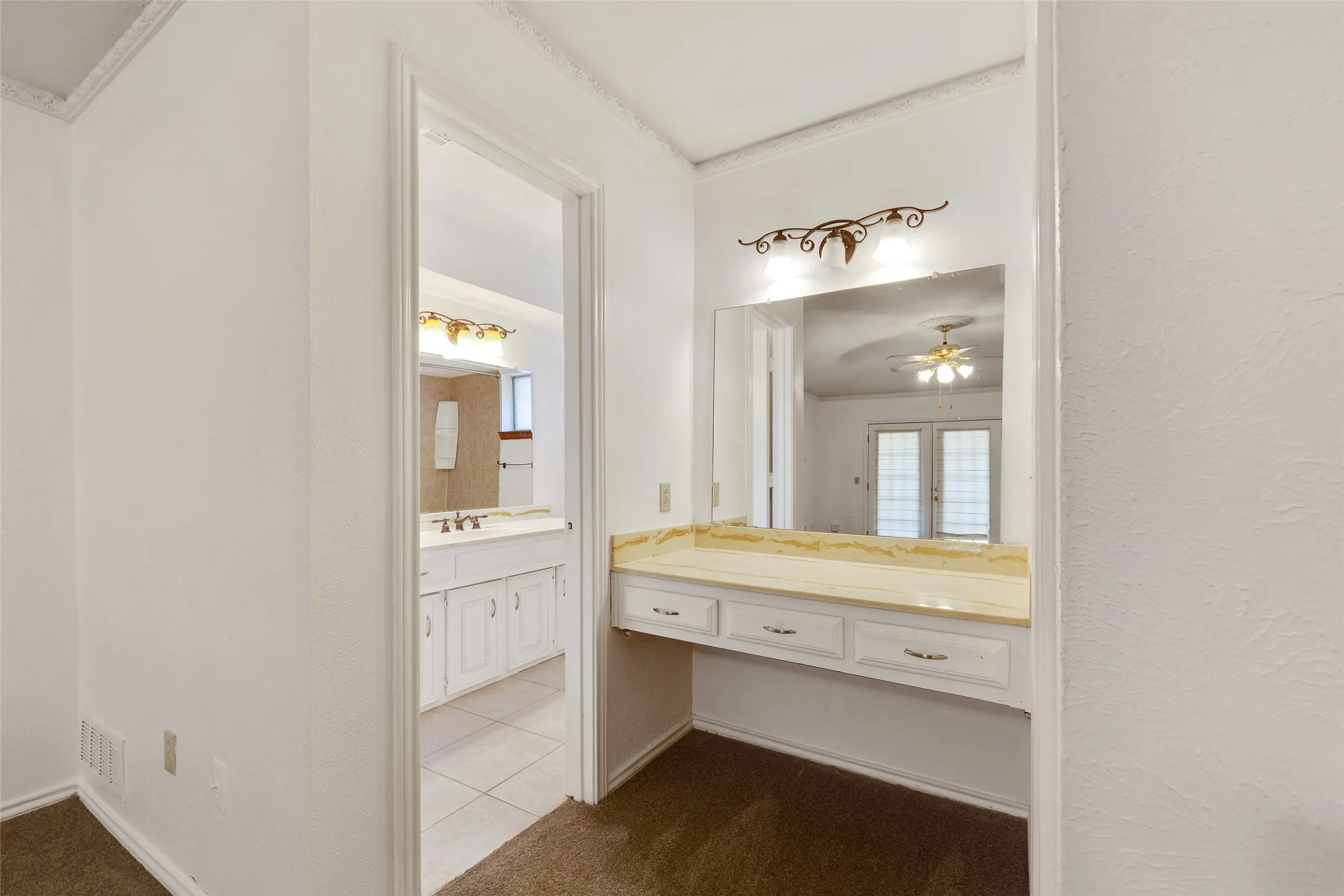 Built-in vanity with a light-colored countertop and integrated mirror
