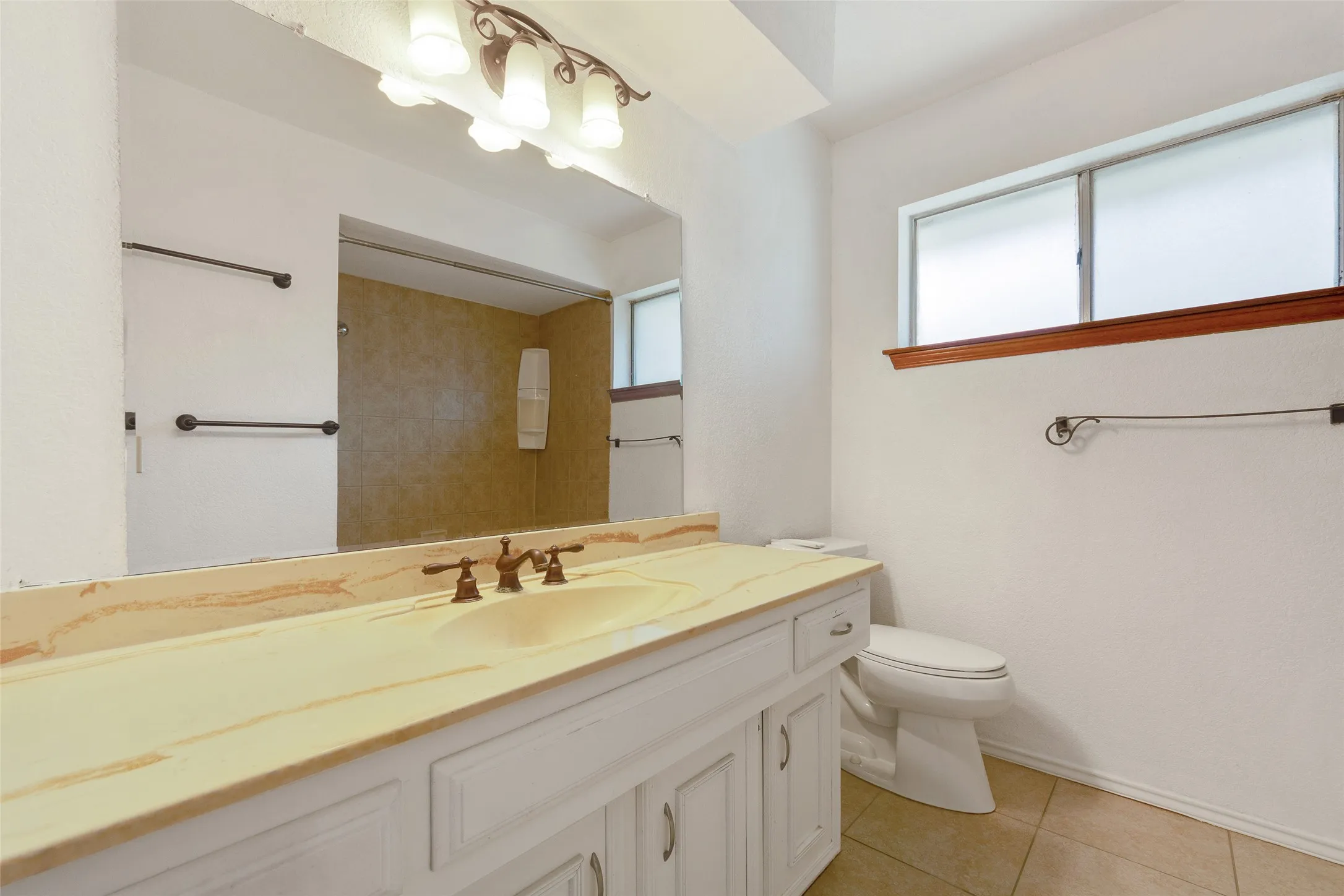 Vanity with integrated sink, bronze-finish faucet, and a large mirror