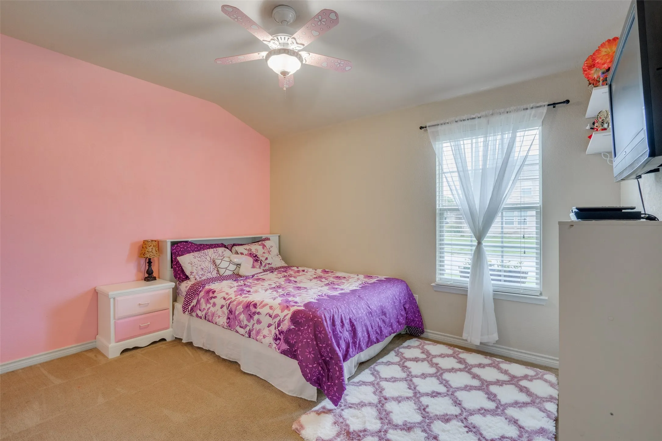 Carpeted room with vaulted ceiling and ceiling fan with integrated lighting