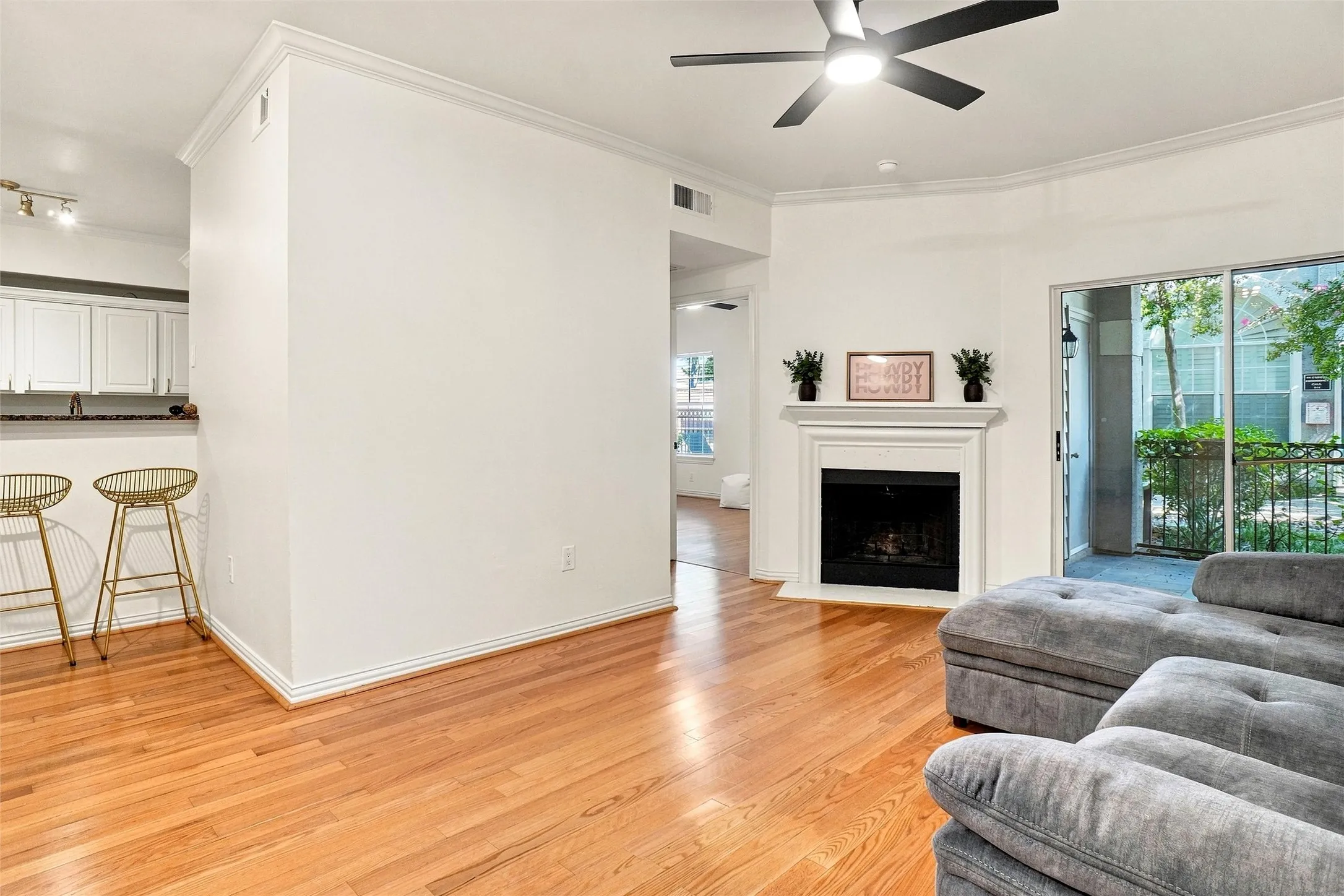 Wood-finish flooring throughout, a built-in fireplace with mantel, crown molding, and a ceiling fan with integrated lighting