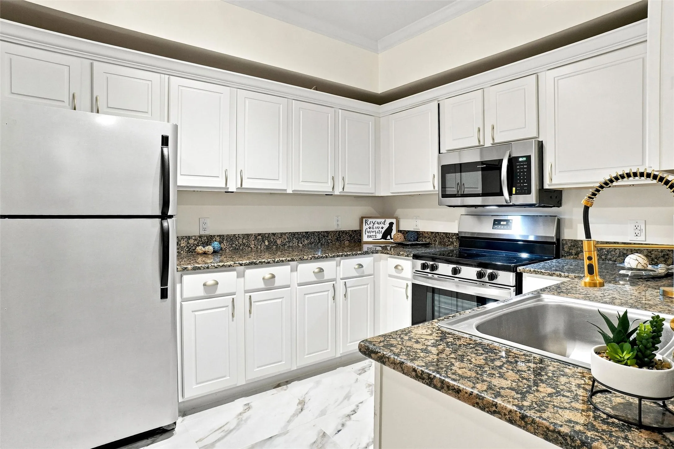 Kitchen featuring white cabinetry, granite-style countertops, stainless steel appliances, and a stainless steel sink with a flexible faucet