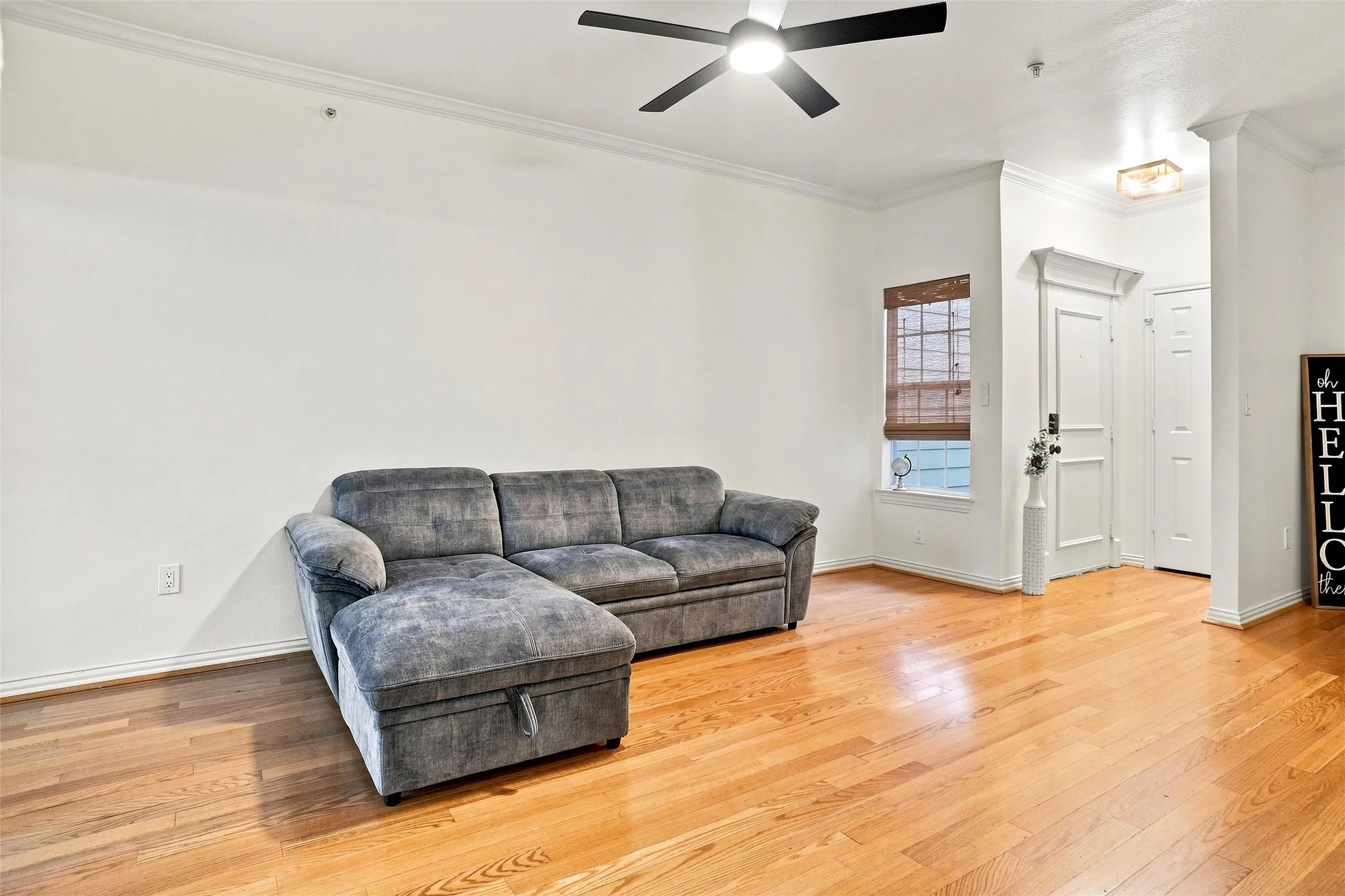 Wood-finish flooring, crown molding, and a ceiling fan with integrated lighting