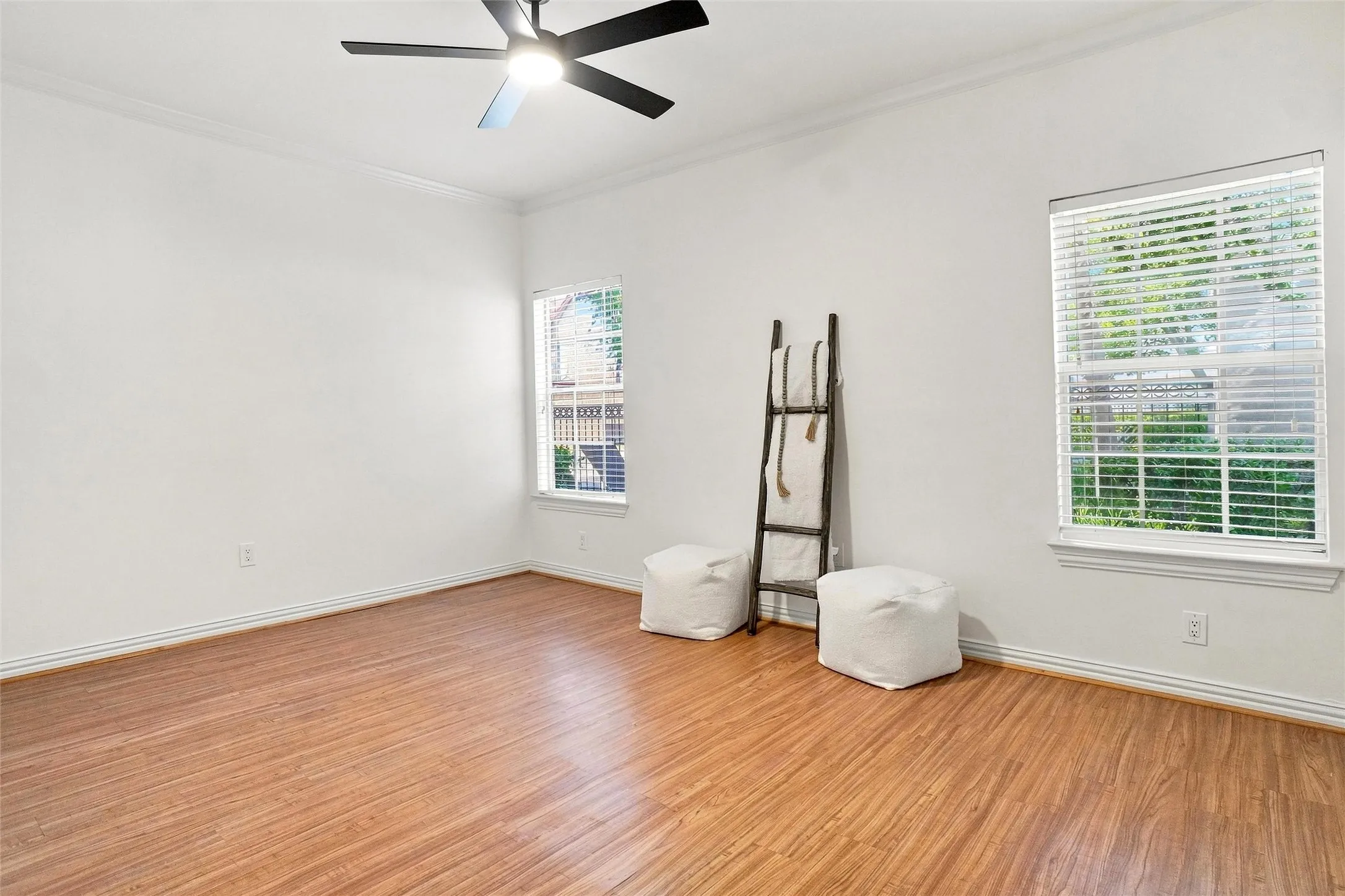 Wood-finish flooring, white walls, and crown molding