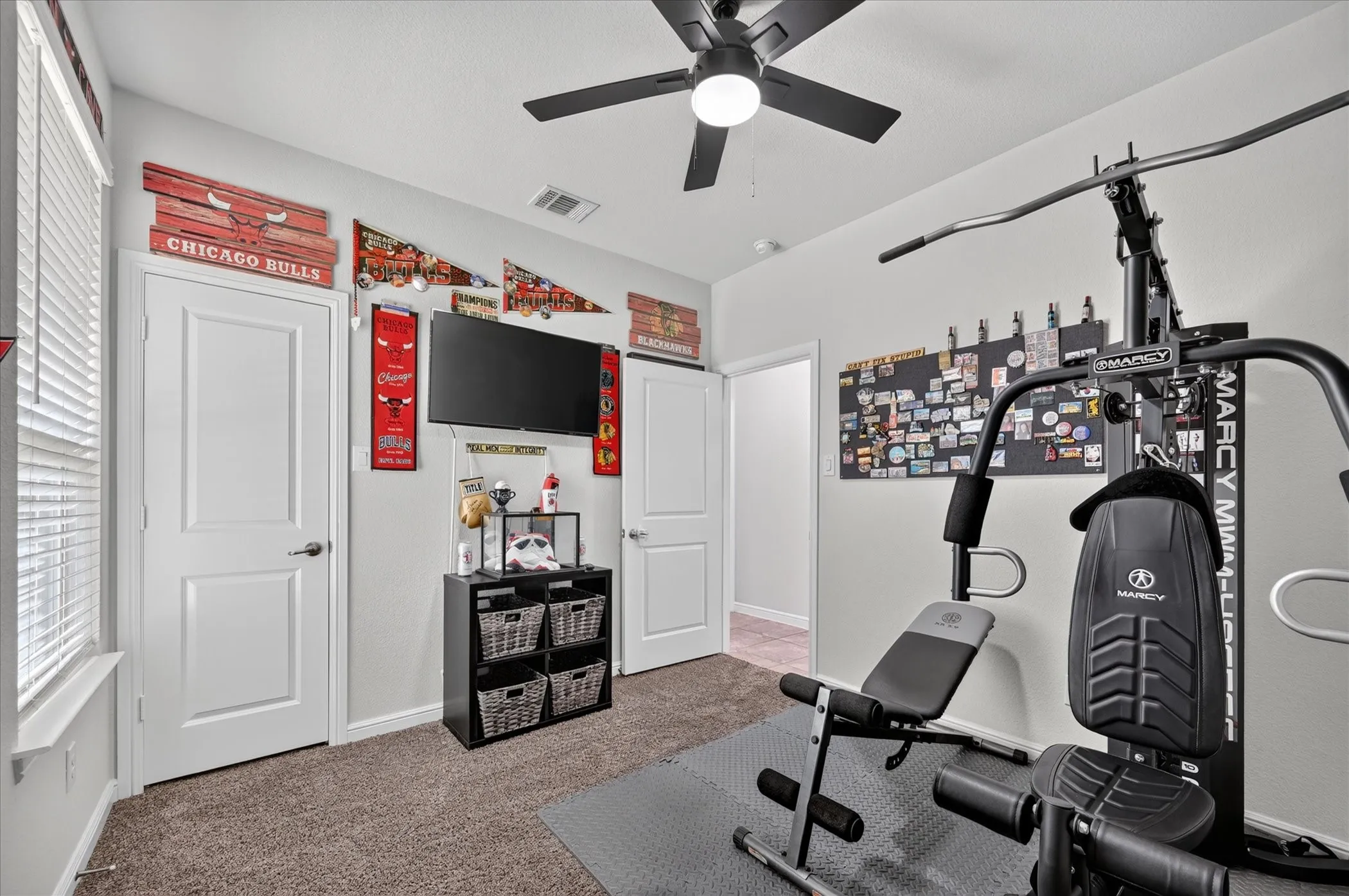Carpeted room with a ceiling fan, window with blinds, and white interior doors