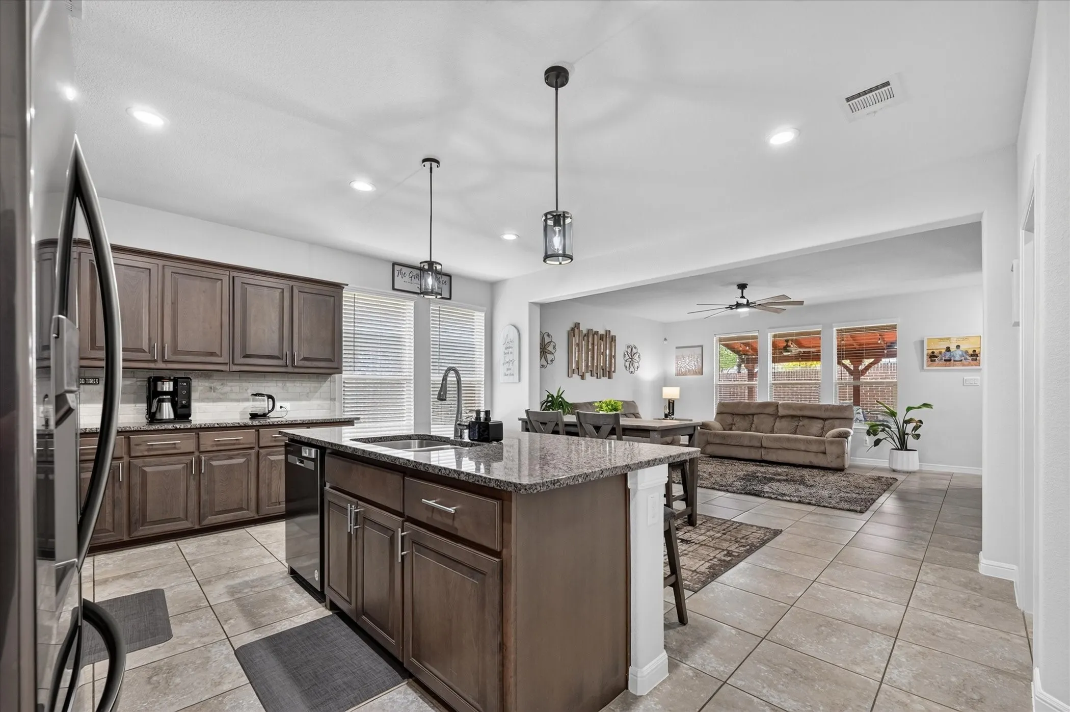 Kitchen featuring wood-finish cabinetry, granite countertops, tile flooring, and a stainless steel dishwasher