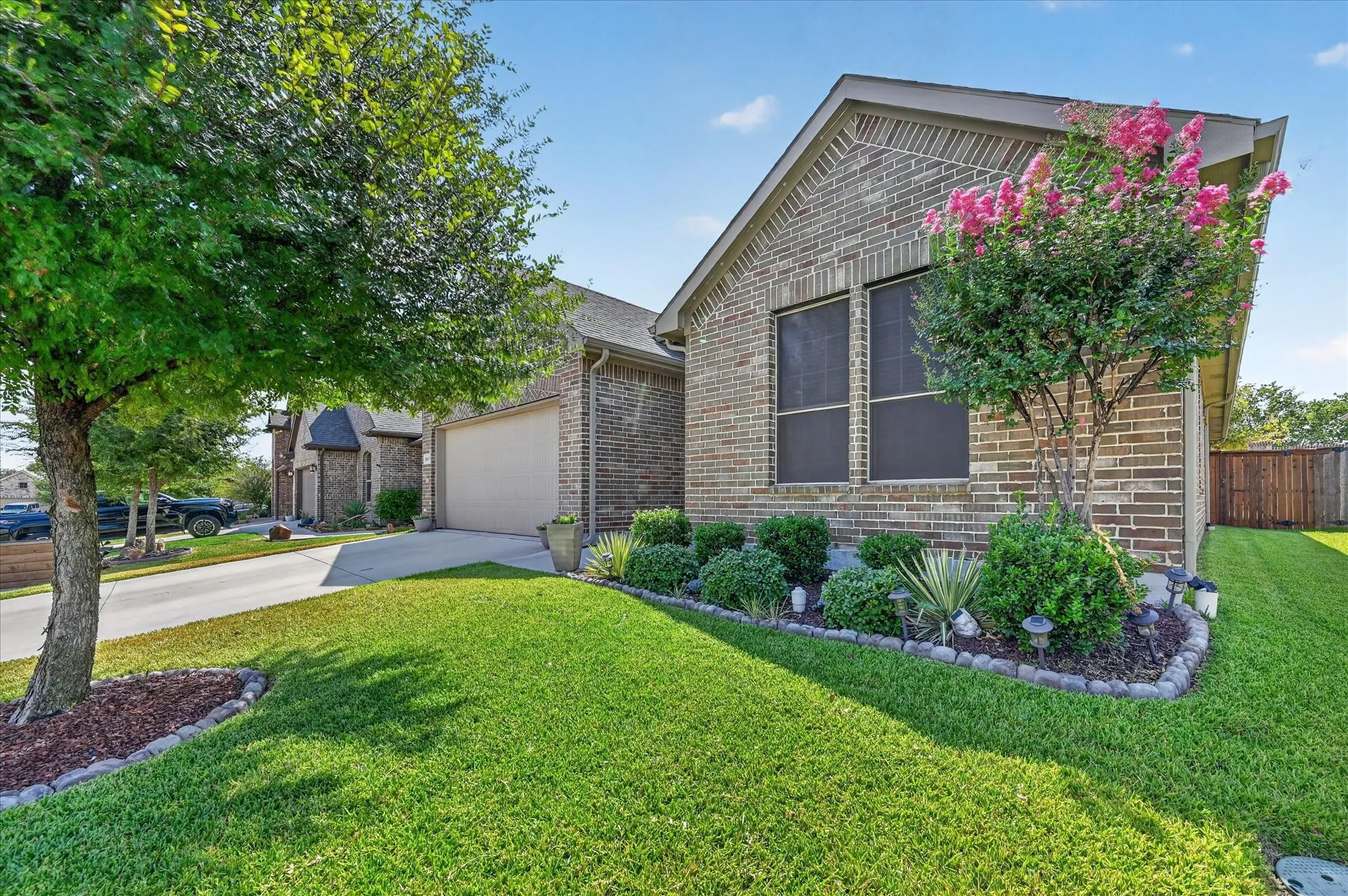 Brick exterior with an attached garage, featuring a well-maintained lawn and established landscaping