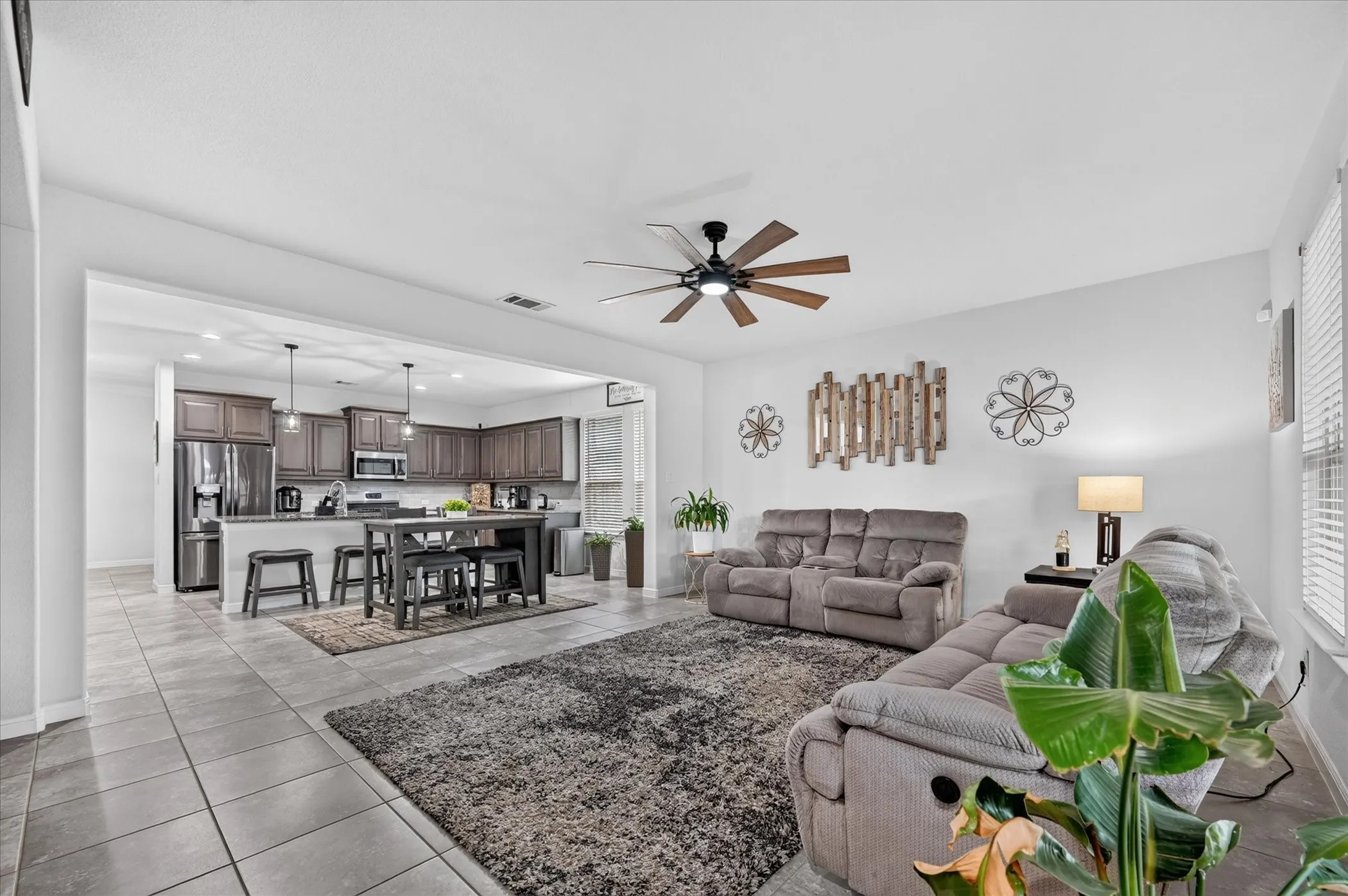 Spacious living area with tile flooring, a ceiling fan, and window blinds