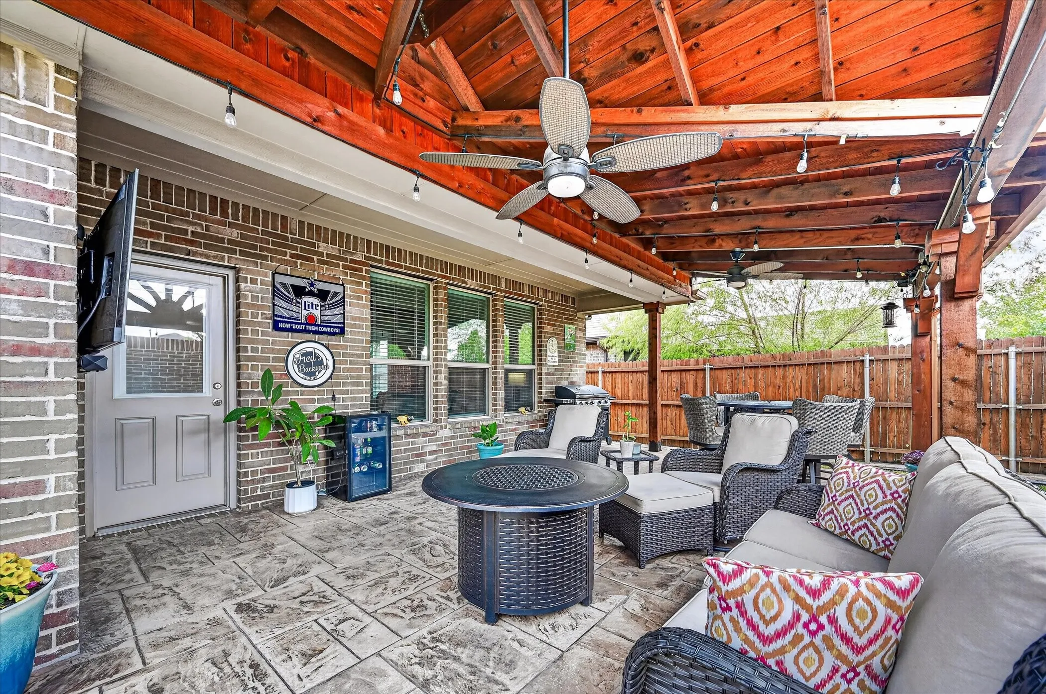 Covered patio featuring a stained wood ceiling, multiple ceiling fans, and string lighting