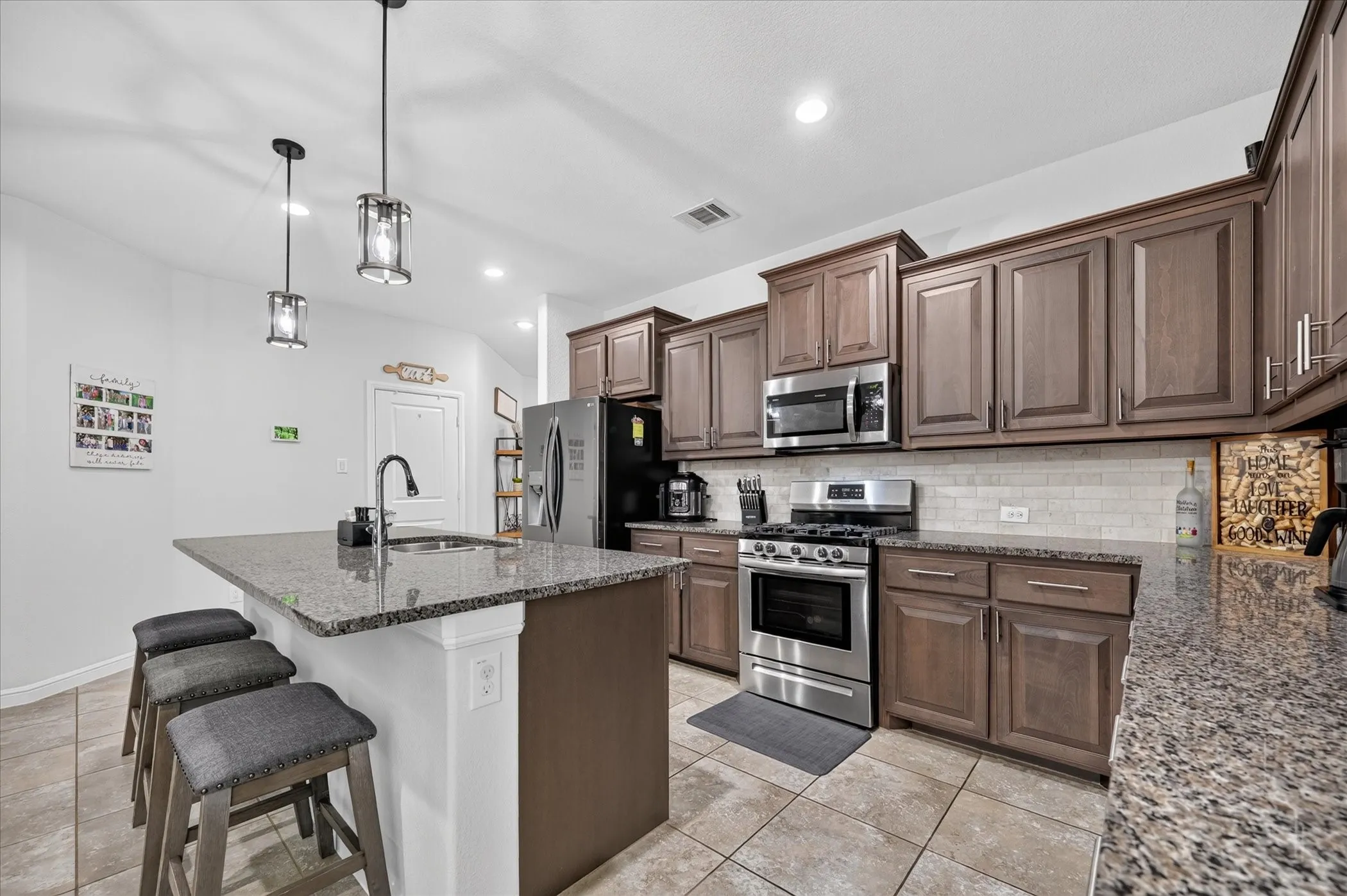 Granite countertops, stainless steel appliances, tile flooring, rich wood-finish cabinetry, and recessed lighting