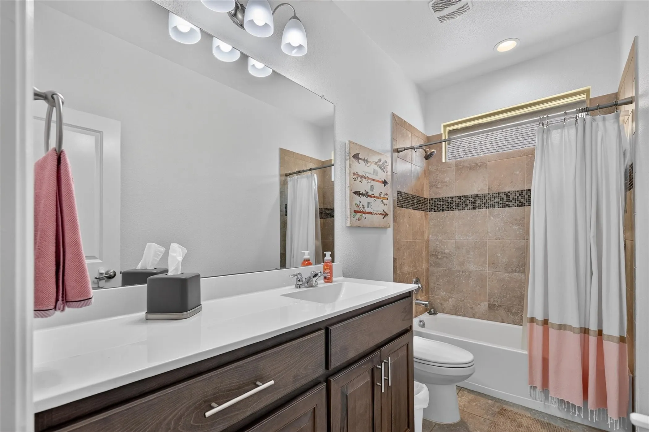 Bathroom featuring a single vanity with dark wood-finish cabinetry, a white countertop, and a large mirror