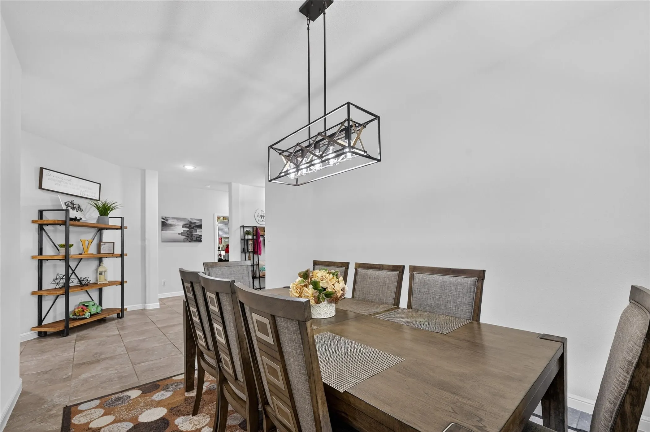 Recessed lighting and a modern linear chandelier illuminate the dining area, featuring tile flooring