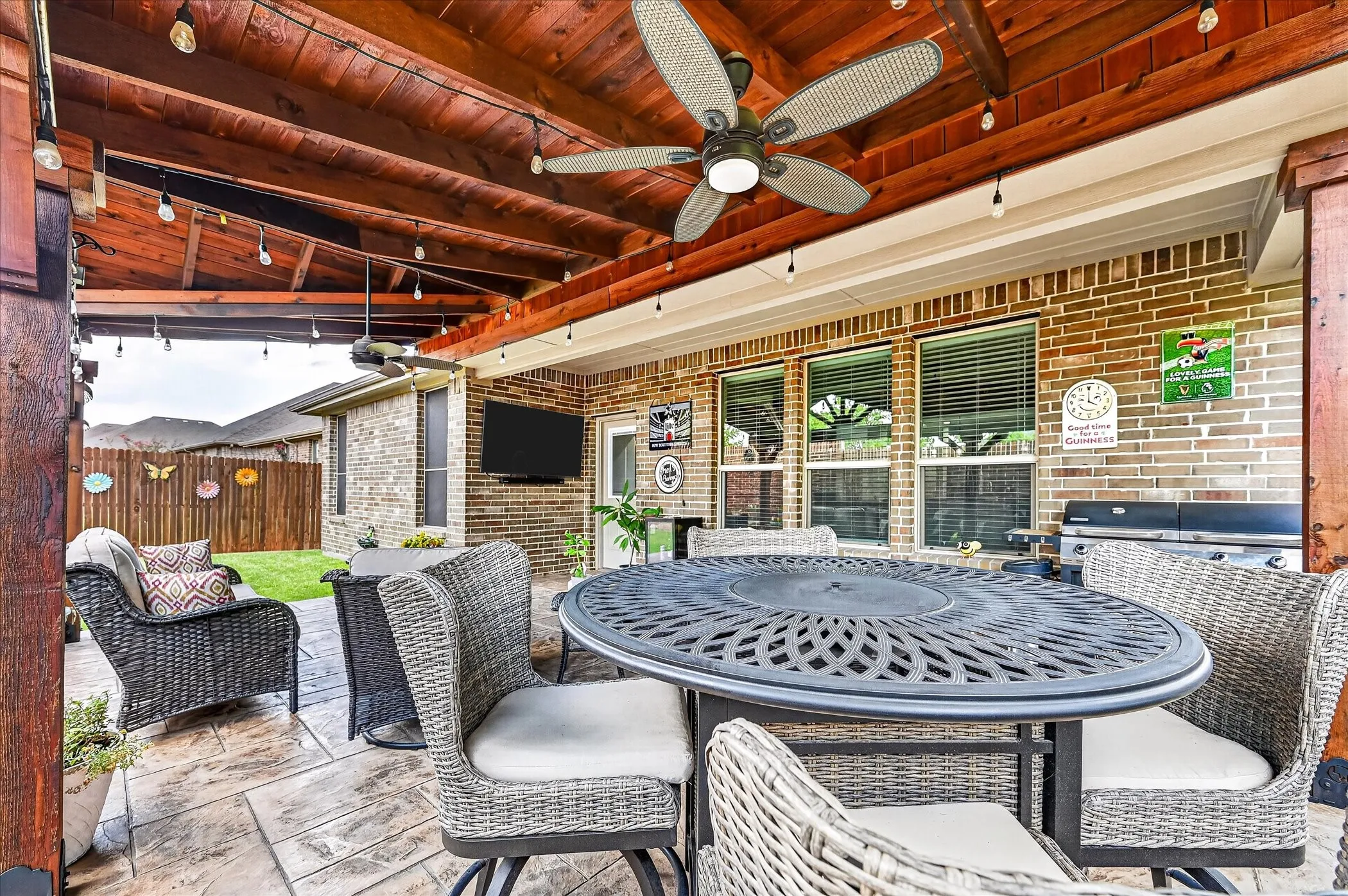 Covered patio featuring an exposed wood ceiling, multiple ceiling fans, string lighting, and stamped concrete flooring