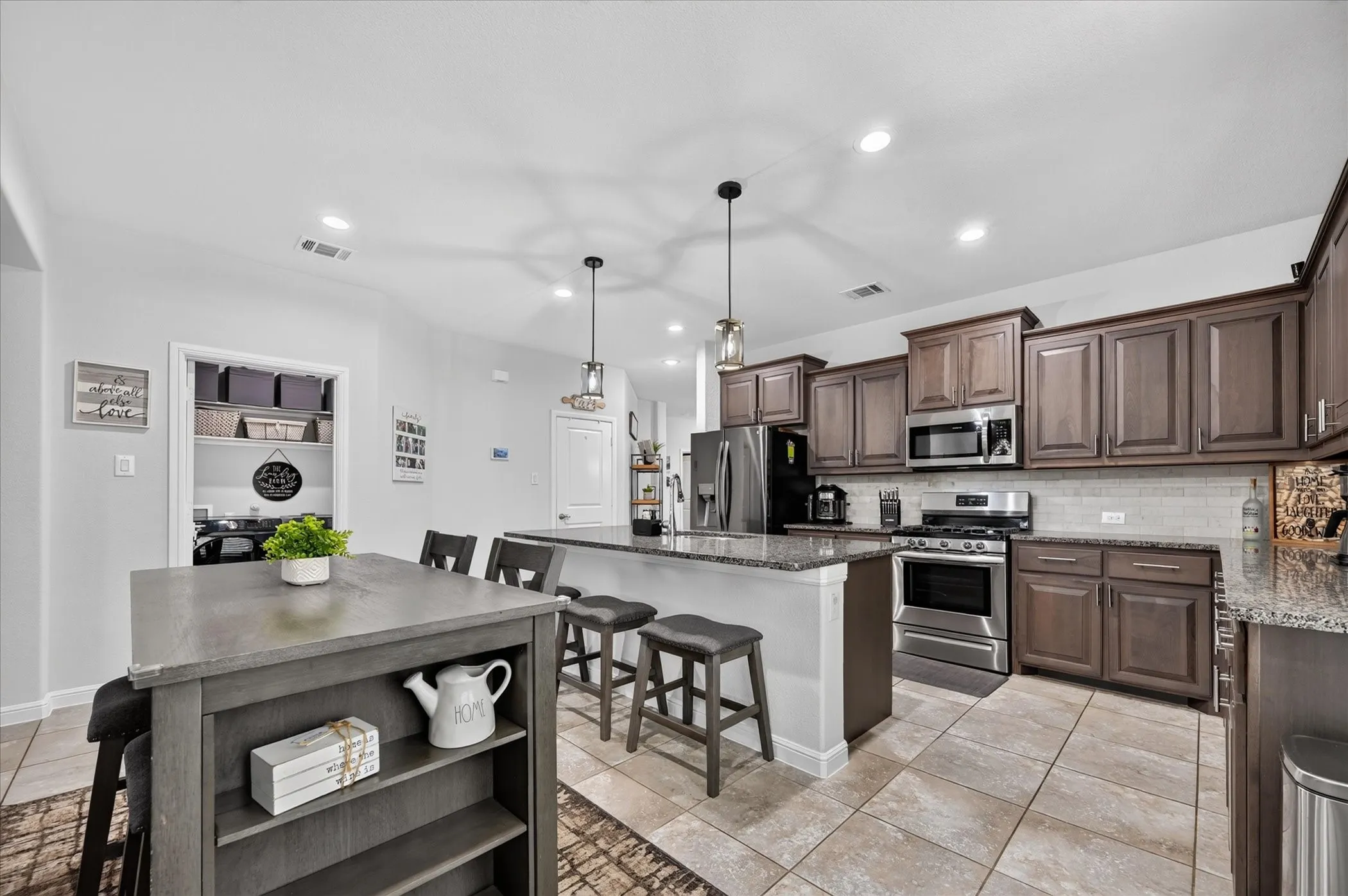 Chef's kitchen featuring wood-finish cabinetry, stainless steel appliances, tile flooring, and a large center island with seating