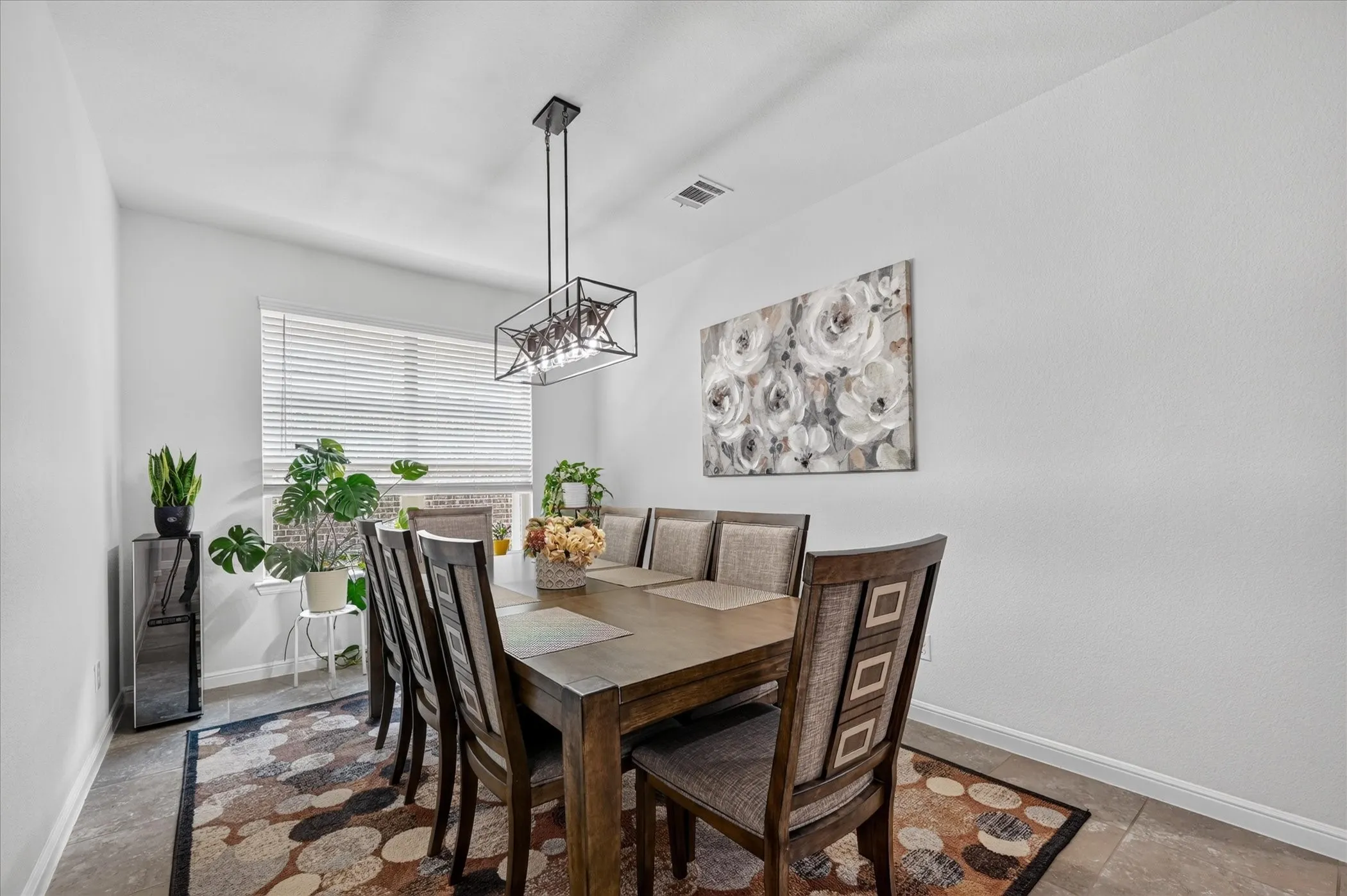 Window with horizontal blinds, overhead linear chandelier with exposed bulbs, and tile flooring