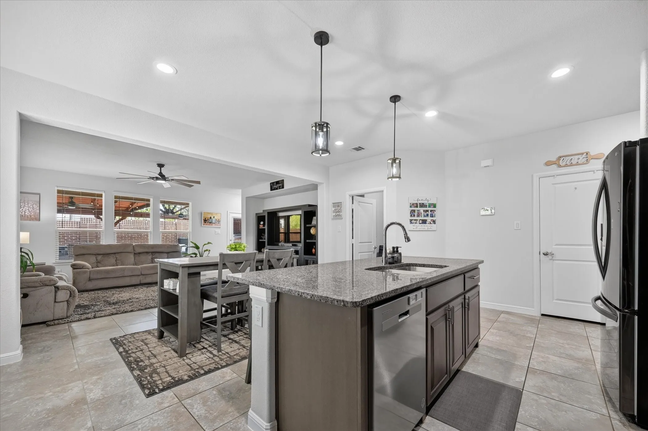 Kitchen island with a granite countertop, dark wood-finish cabinetry, and stainless steel dishwasher