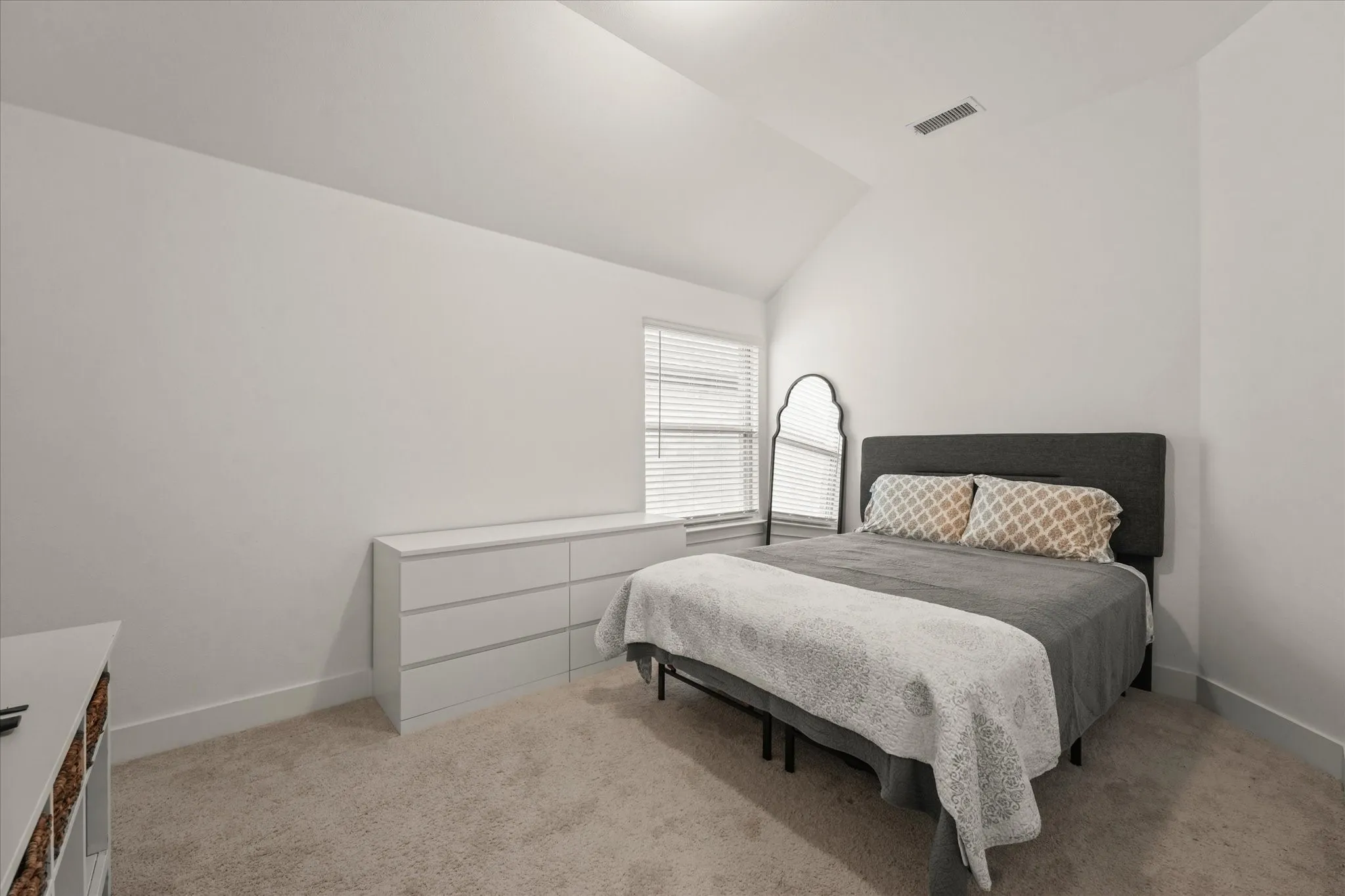 Vaulted ceiling with bright white walls, wall-to-wall carpeting, and a built-in window with white blinds