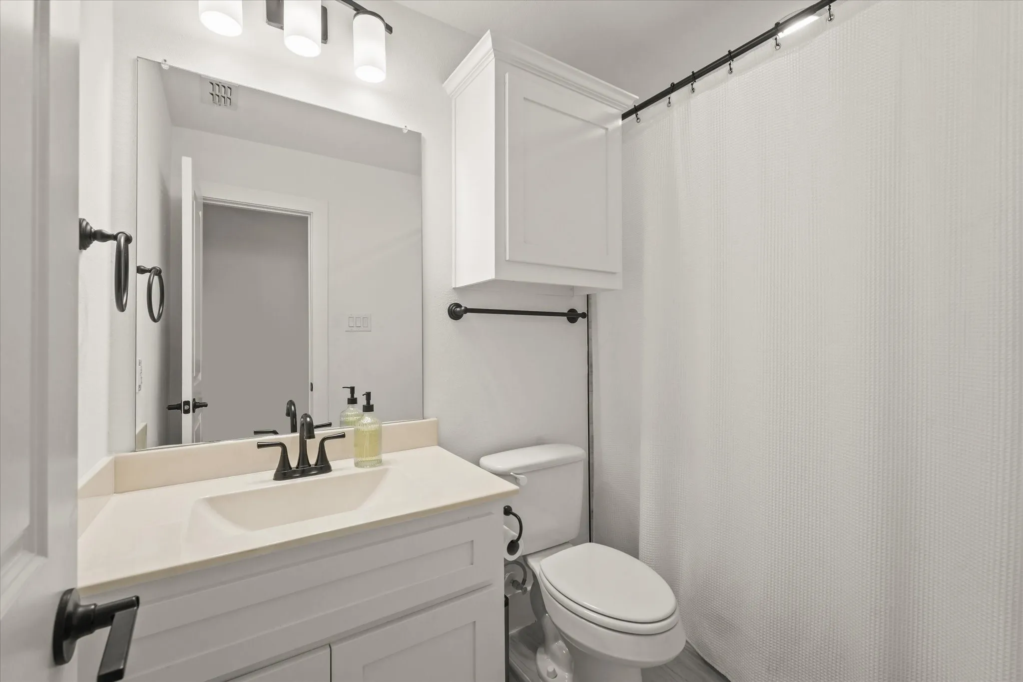 White vanity with an integrated sink, dark bronze-finish hardware, and a framed mirror