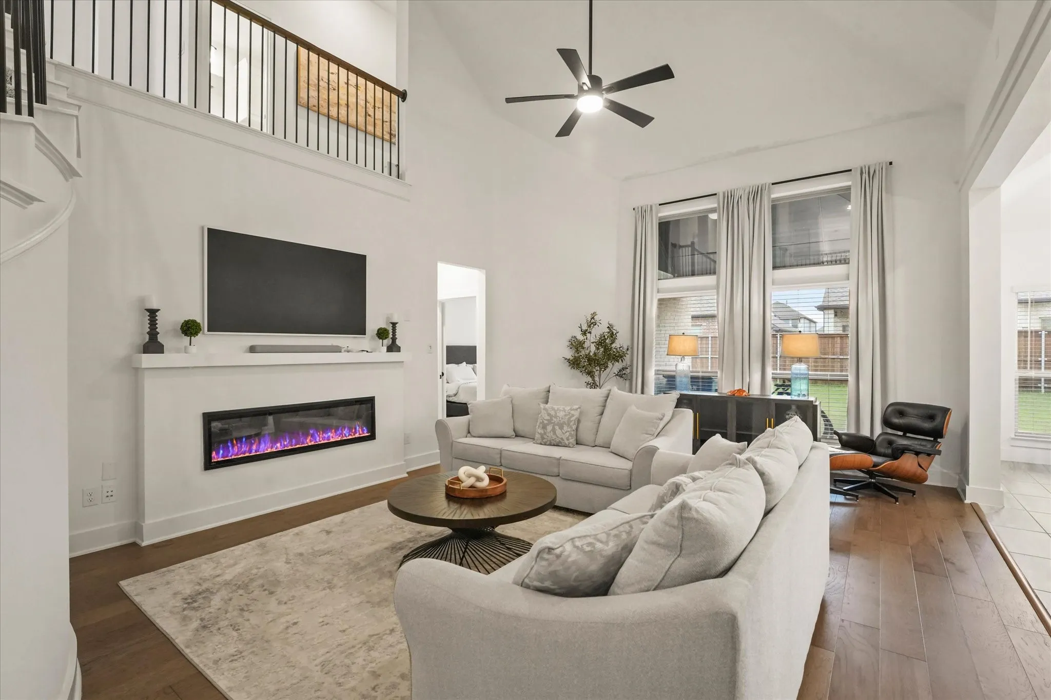 Living room with wood-finish flooring, a contemporary electric fireplace, and vaulted ceilings