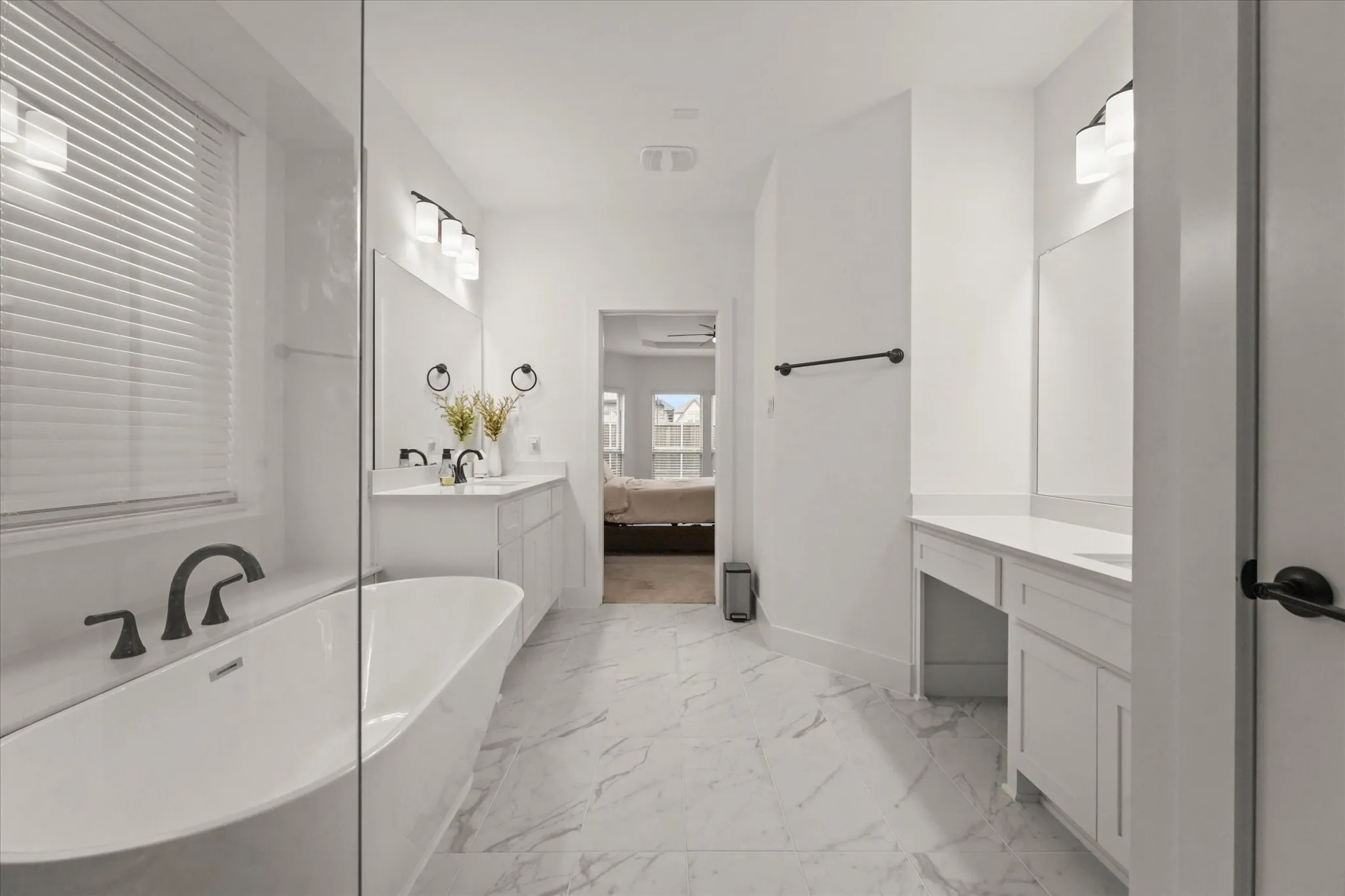 Freestanding soaking tub with dark-finish fixtures, dual vanity with undermount sinks, and a separate vanity area