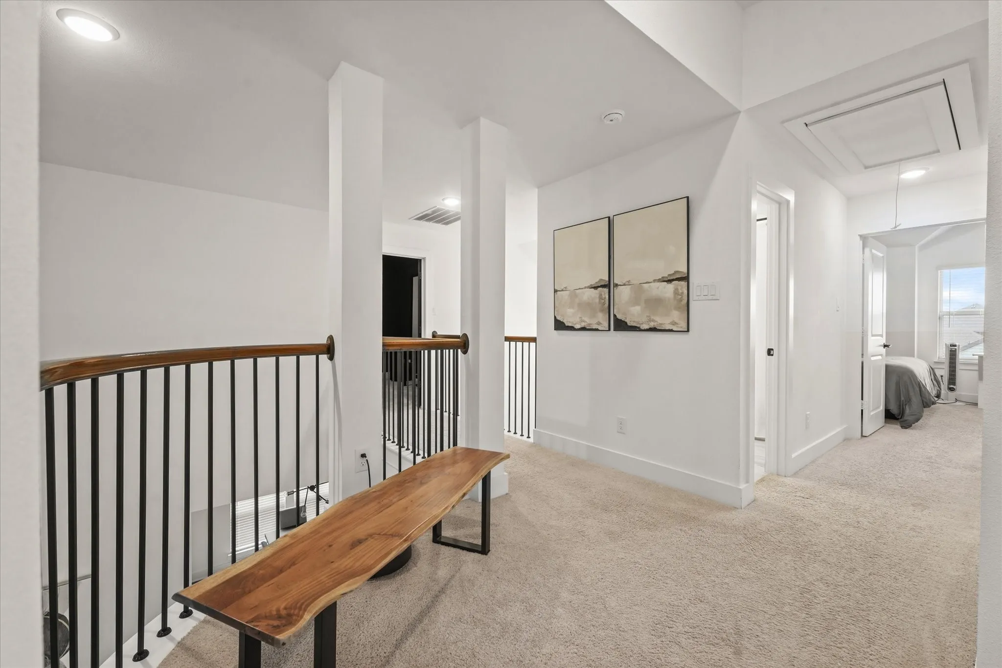Upper level landing featuring carpeted flooring, recessed lighting, and a wood-finish handrail with black metal balusters