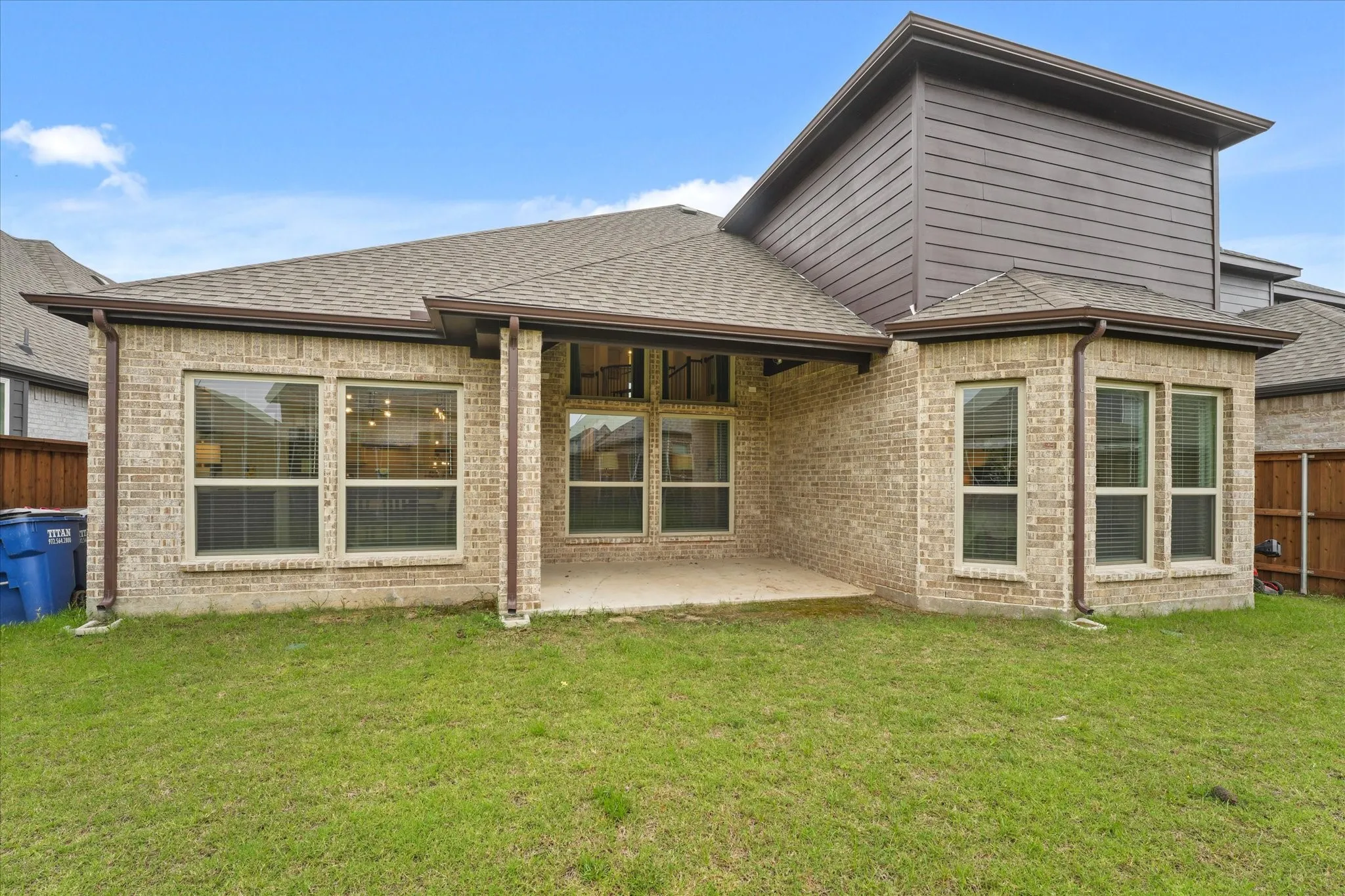 Rear exterior featuring a covered patio, brick and horizontal siding facade, and multiple windows