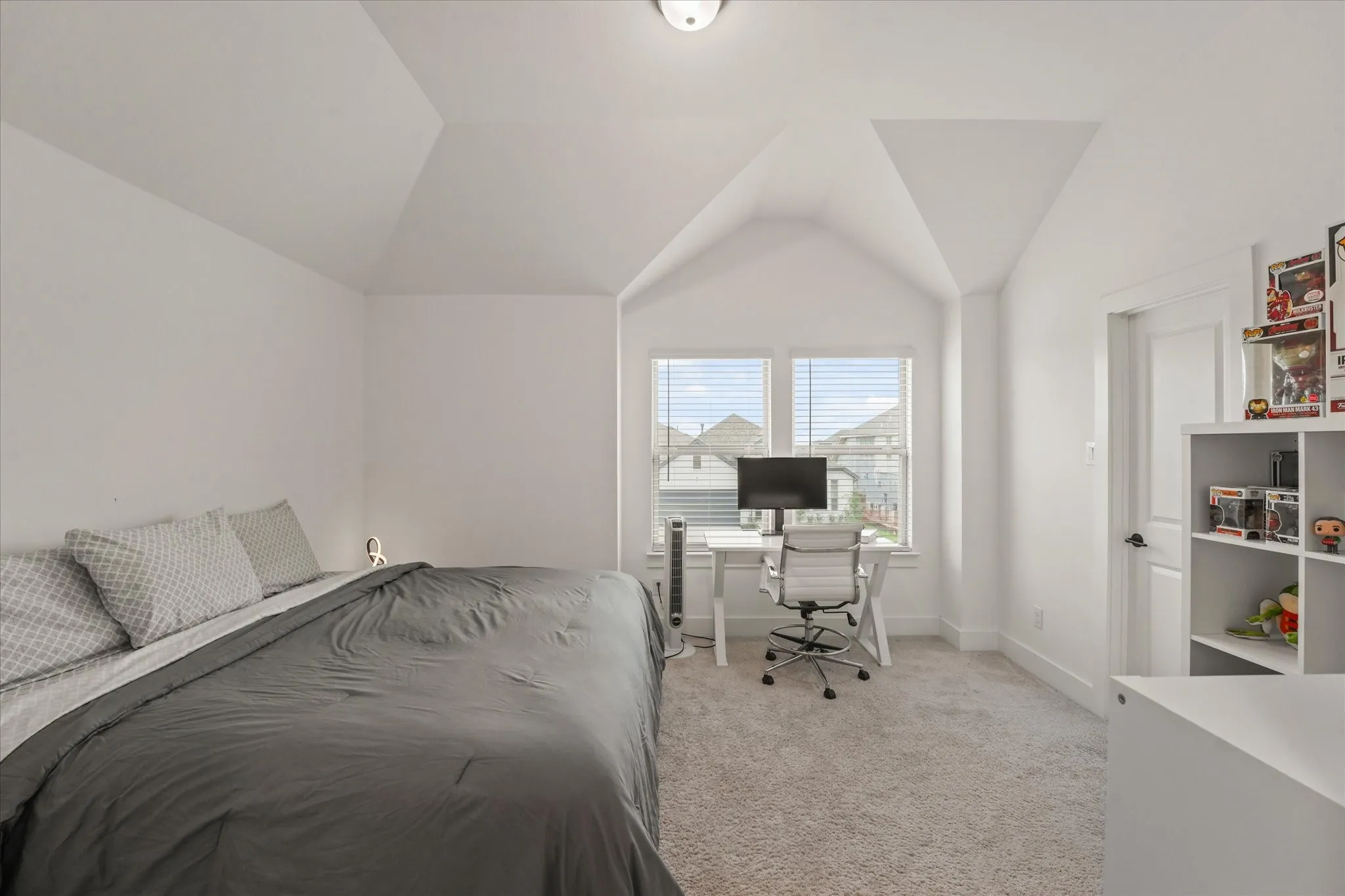 Vaulted ceiling with a flush-mount light fixture, white walls, and light-toned carpeting