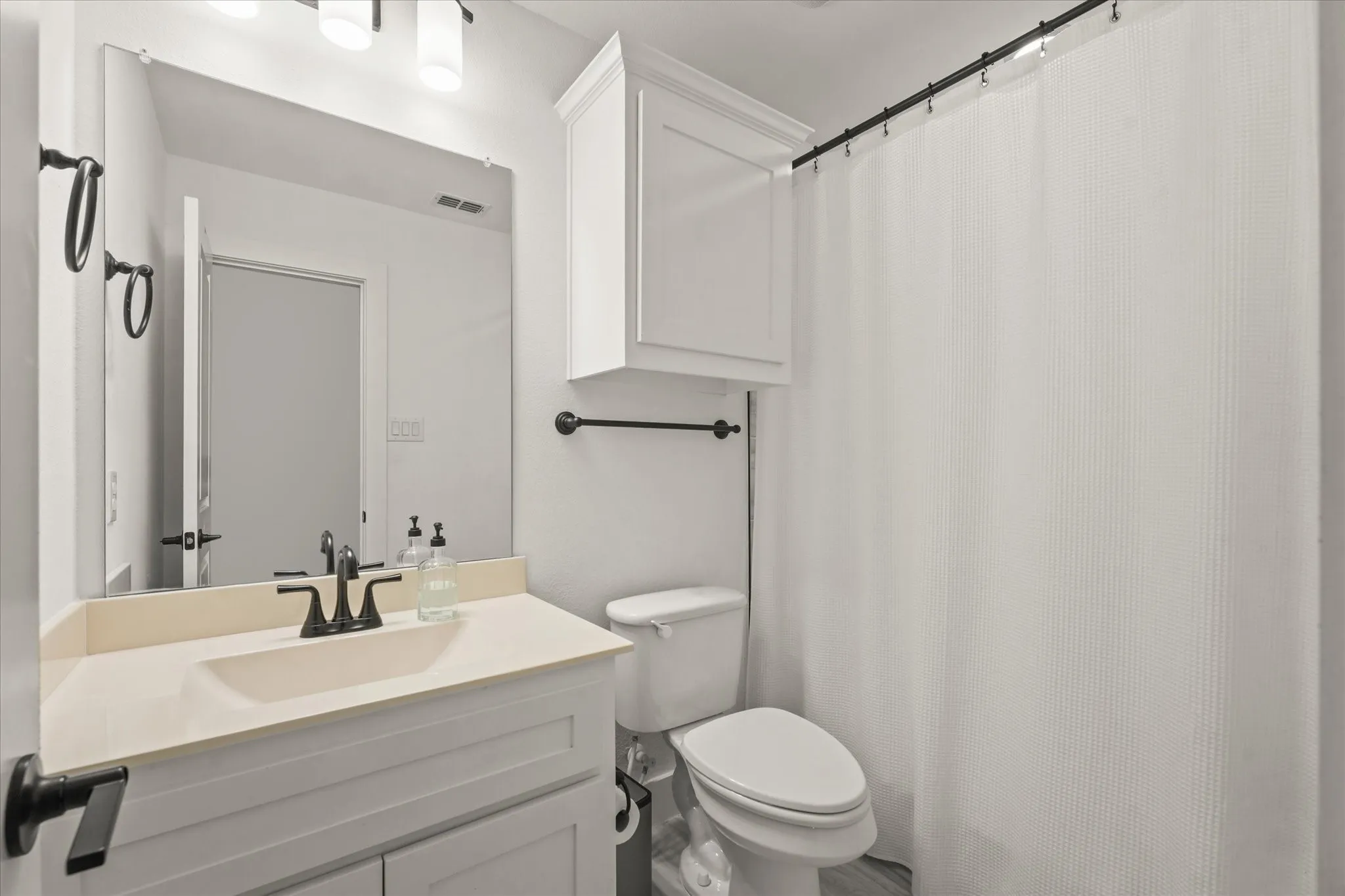 White vanity with an integrated rectangular sink, matte black faucet, and a large wall-mounted mirror