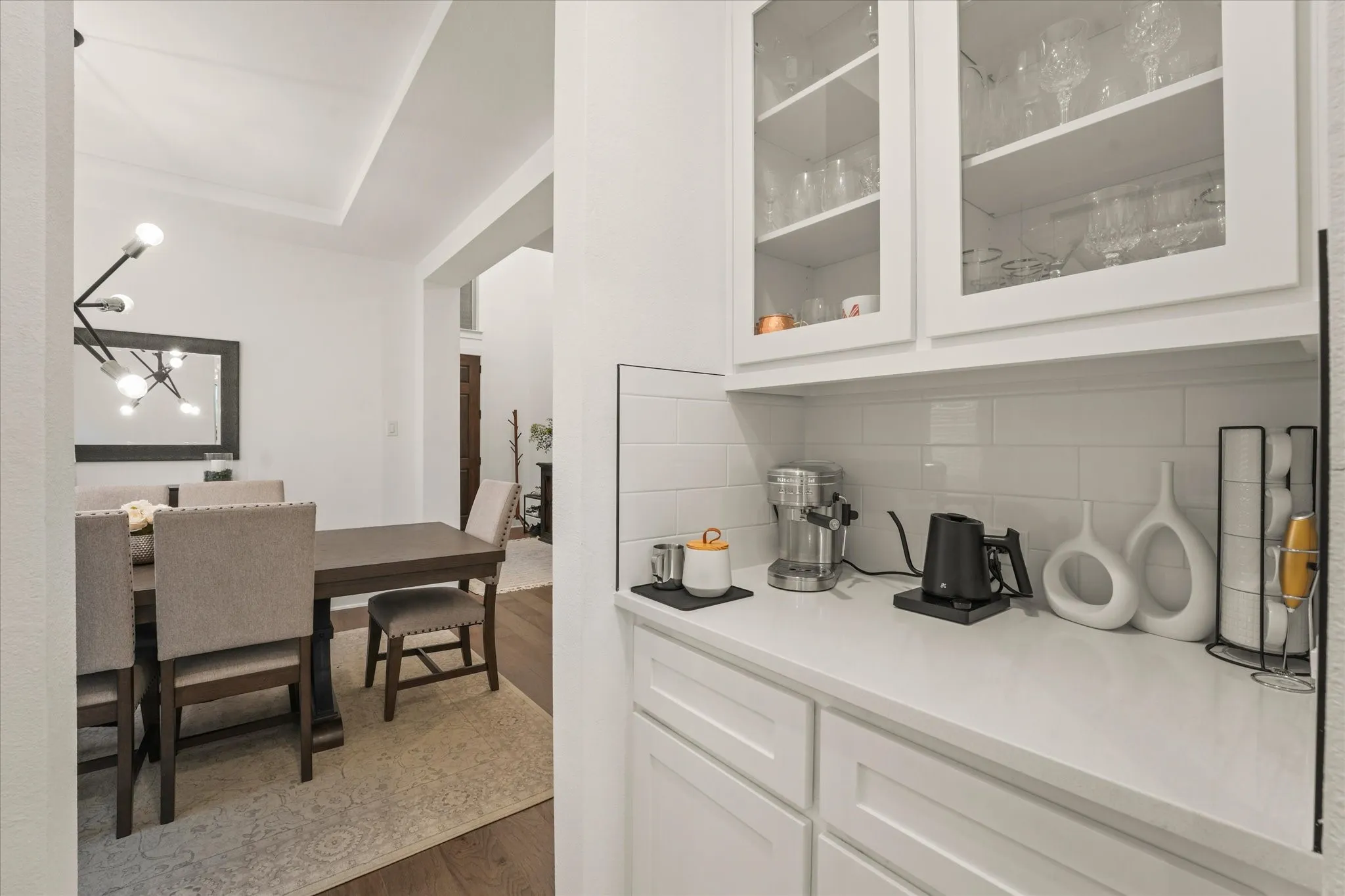 Built-in coffee bar featuring white cabinetry, glass-front upper cabinets, subway tile backsplash, and light-toned countertop