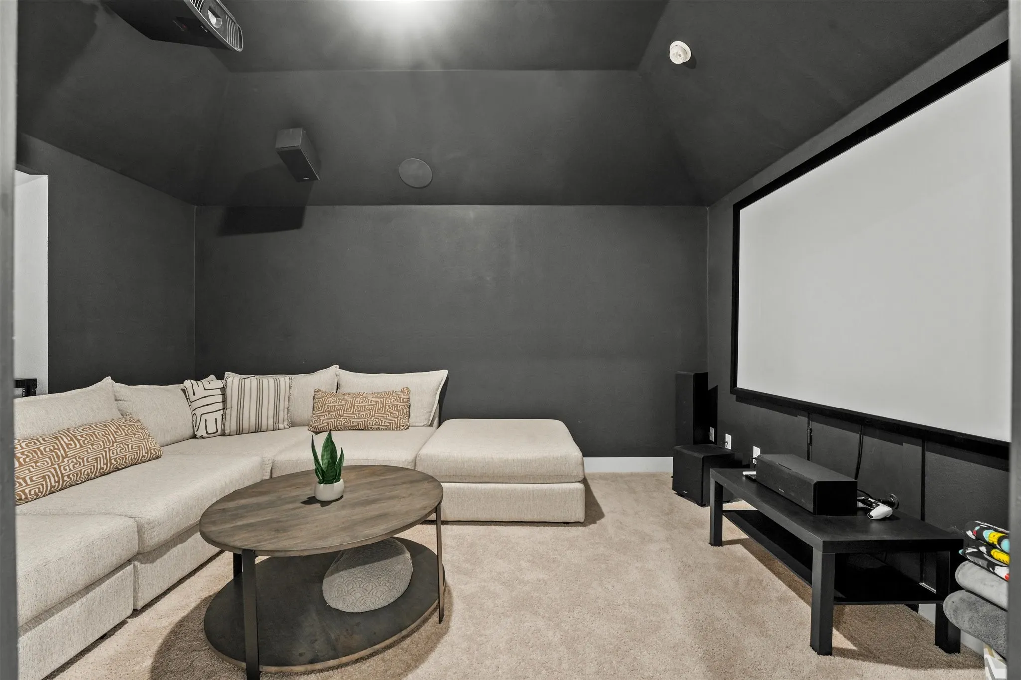 Projector screen, wall-mounted speakers, recessed lighting, wall-mounted projector, and vaulted ceiling