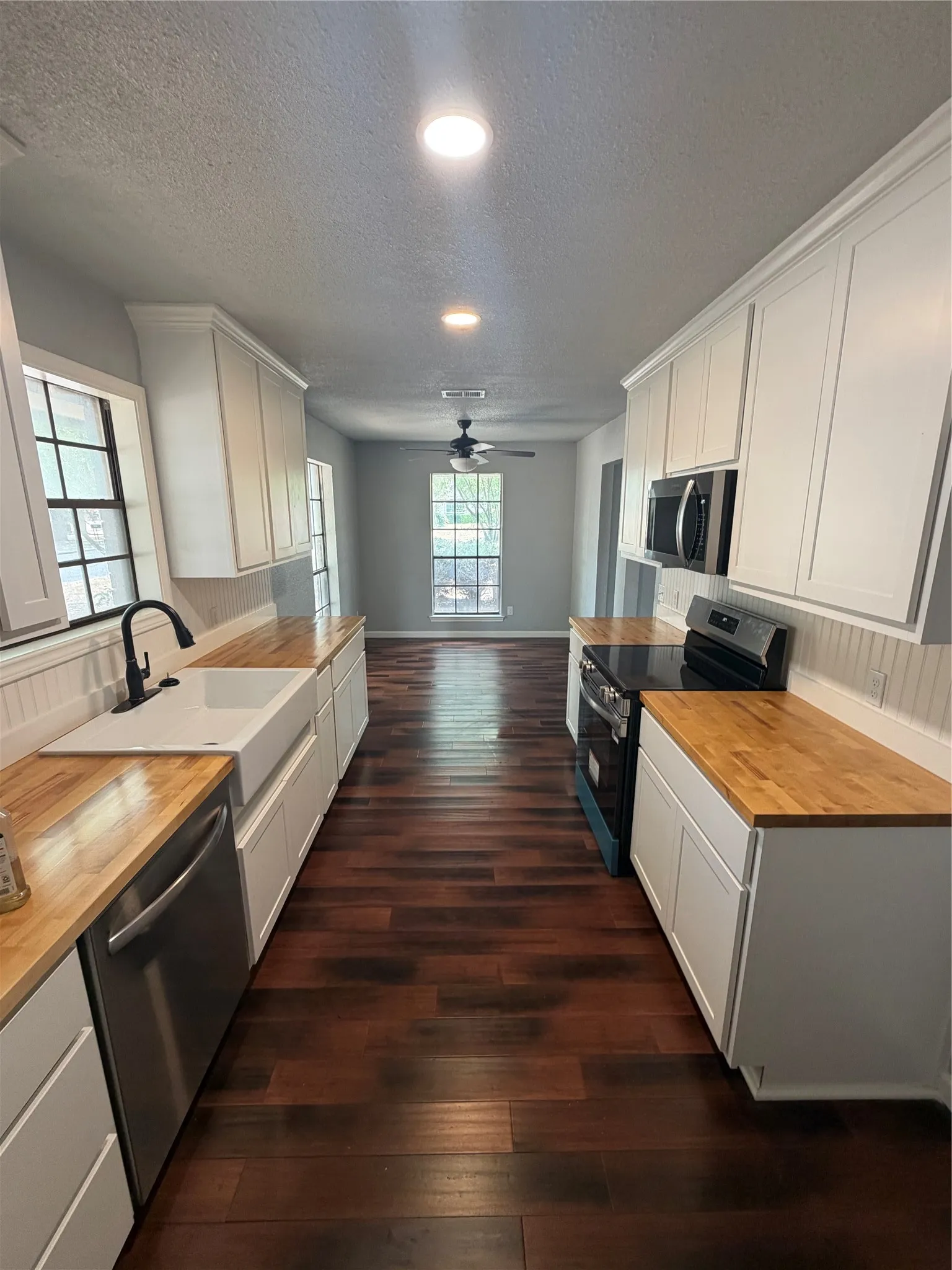 Galley kitchen featuring white cabinetry, wood-finish countertops, and recessed lighting