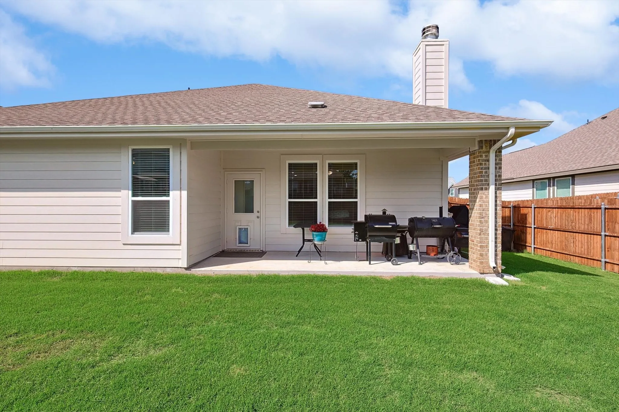 Expansive backyard featuring a covered patio, brick column, and wood privacy fencing