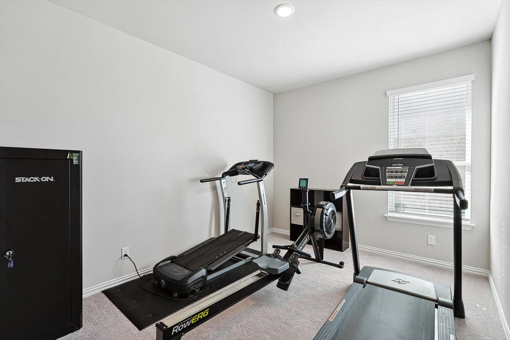Recessed ceiling lighting, a single window with blinds, and light-toned carpeting