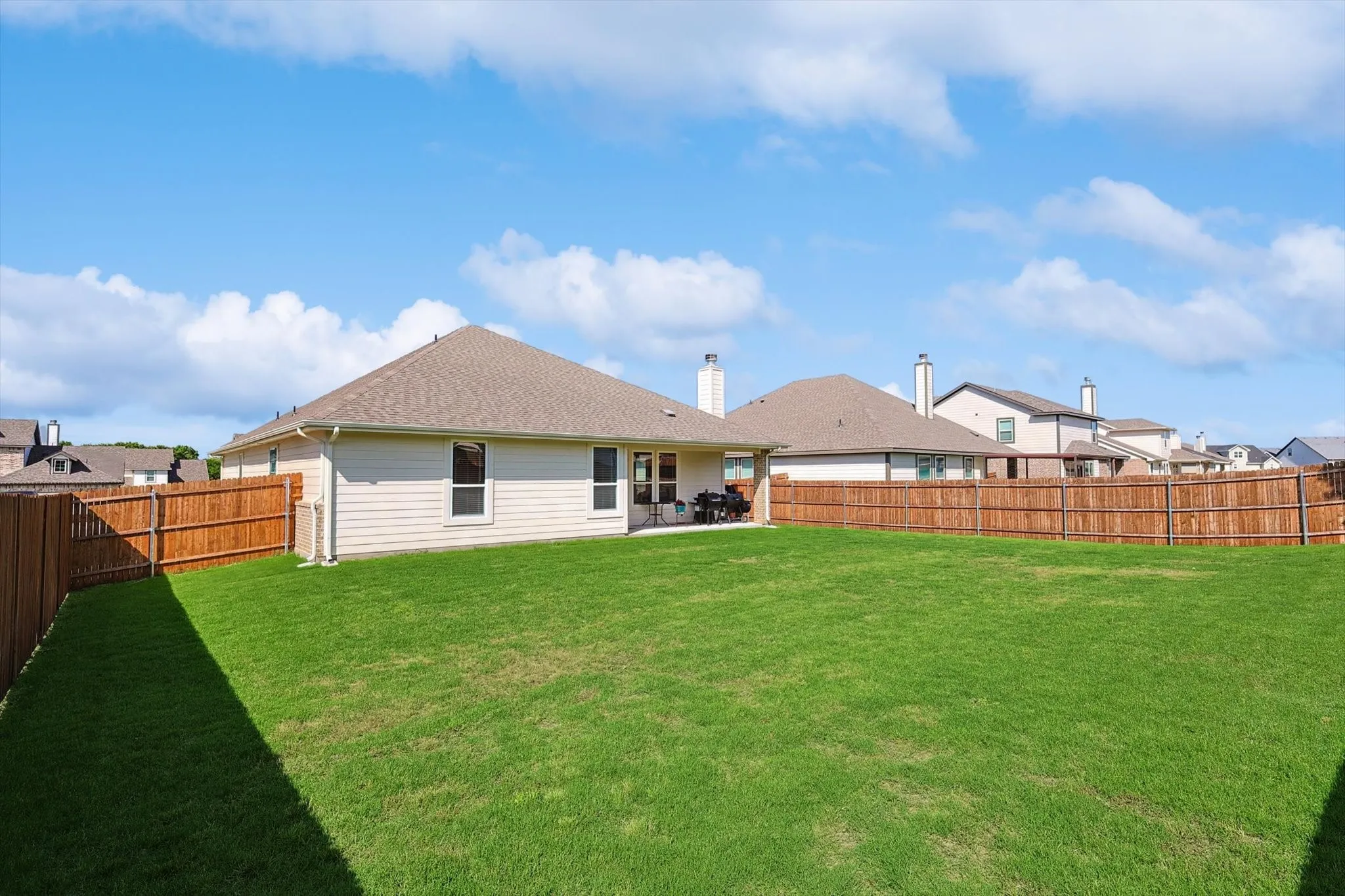 Expansive backyard featuring a manicured lawn, full wood privacy fencing, and rear patio space