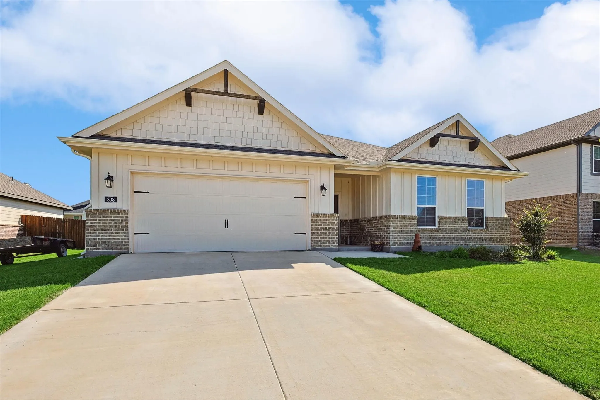 Craftsman-style exterior with stone and siding accents, pitched roofline, attached two-car garage, and concrete driveway