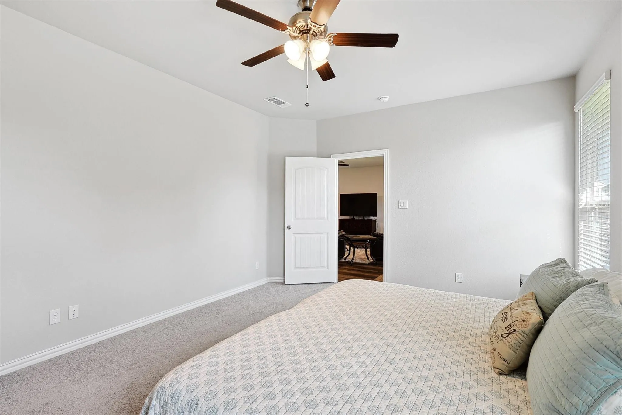 Carpeted room with a ceiling fan light fixture, white walls, and white trim