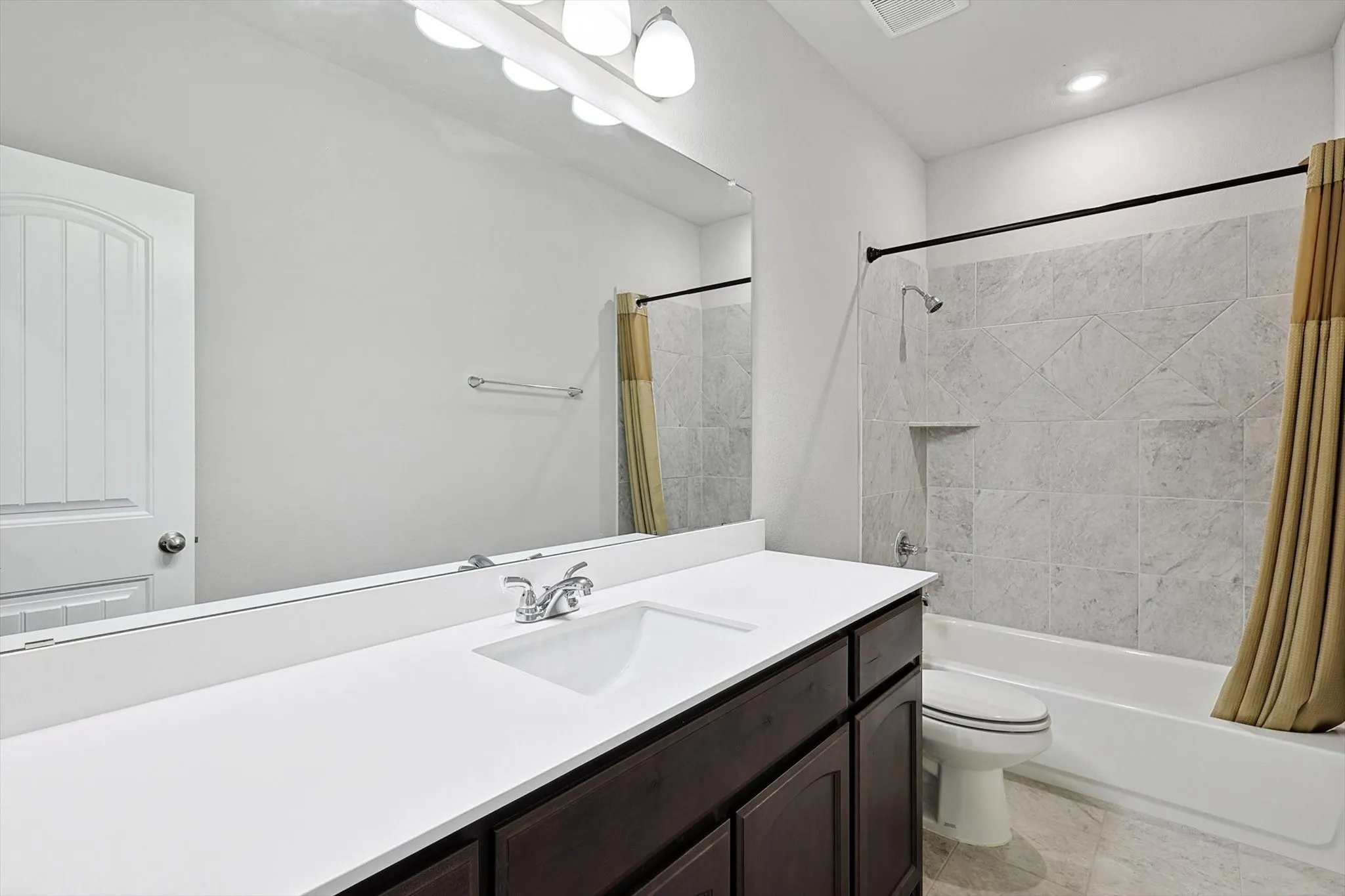 Vanity with integrated sink, expansive mirror, and overhead lighting