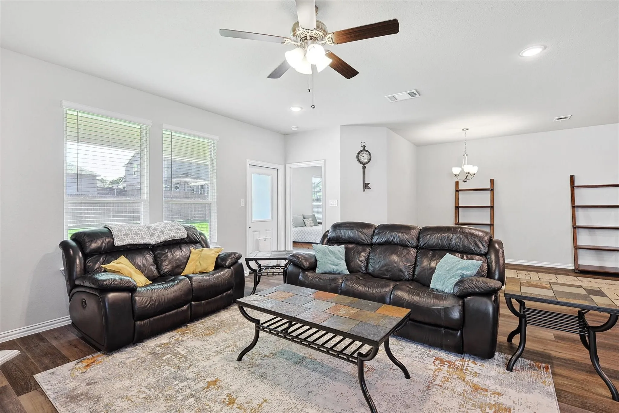 Living area featuring wood-finish flooring, two windows with blinds, recessed lighting, and a ceiling fan with light