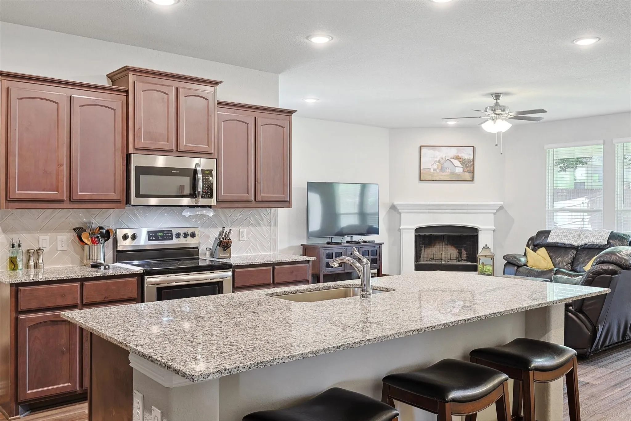 Kitchen featuring wood cabinetry, stainless steel appliances, speckled countertops, and a tile backsplash