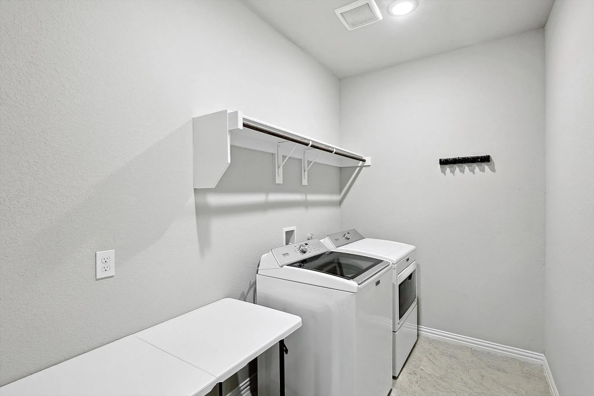 Laundry area with wall-mounted shelving and a clothing rod