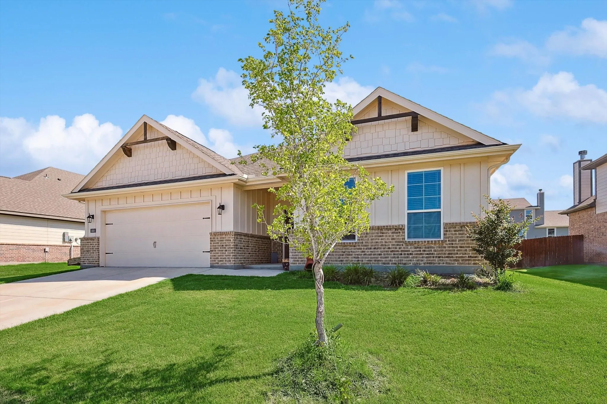 Exterior featuring board and batten siding, brick wainscoting, and an attached two-car garage