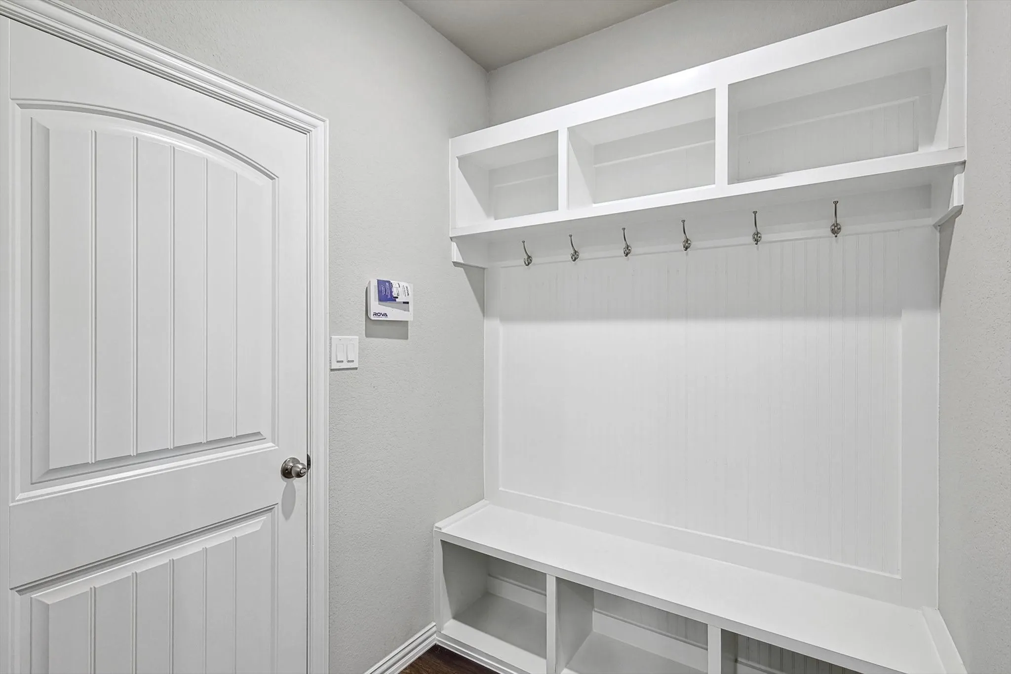 Built-in storage bench with overhead shelving, beadboard backing, and integrated coat hooks