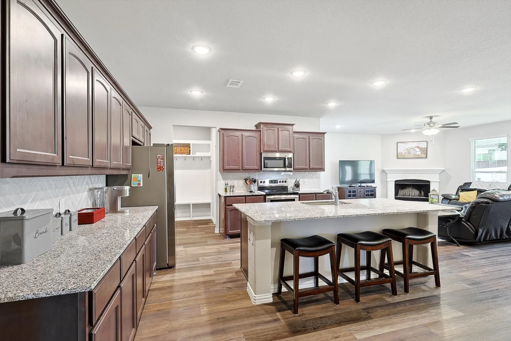 Kitchen with wood-finish flooring, recessed lighting, and a large island featuring stone countertops