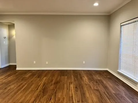 Wood-finish flooring, neutral wall tones, crown molding, recessed lighting, and a window with blinds