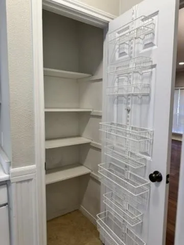 Integrated wire shelving system with multiple storage baskets, adjustable shelving, and light-toned flooring
