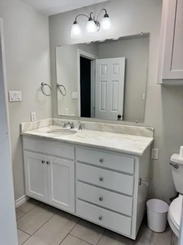 Vanity with a light-toned countertop, integrated sink, and white cabinetry featuring both drawers and cabinet doors