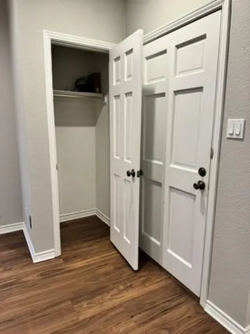 Wood-finish flooring, white paneled bifold doors, white trim, and light gray wall paint