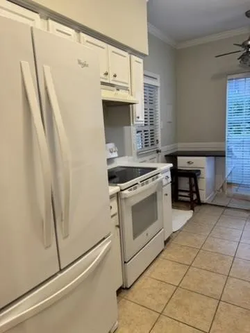 Kitchen featuring white cabinetry, white appliances, tile flooring, and a ceiling fan